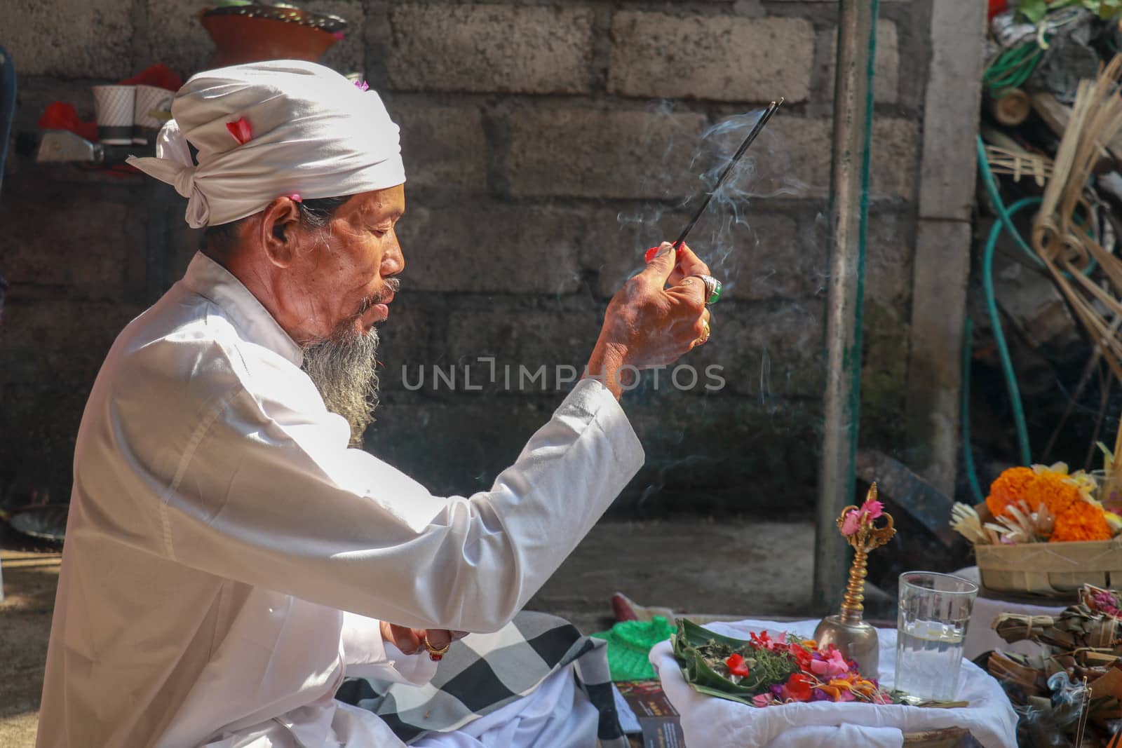 Close up of a Balinese pedanda during prayer. side view of a hindu priest performing a ceremony. A hindu priest performing offerings in a temple in Pemuteran in Bali, Indonesia.