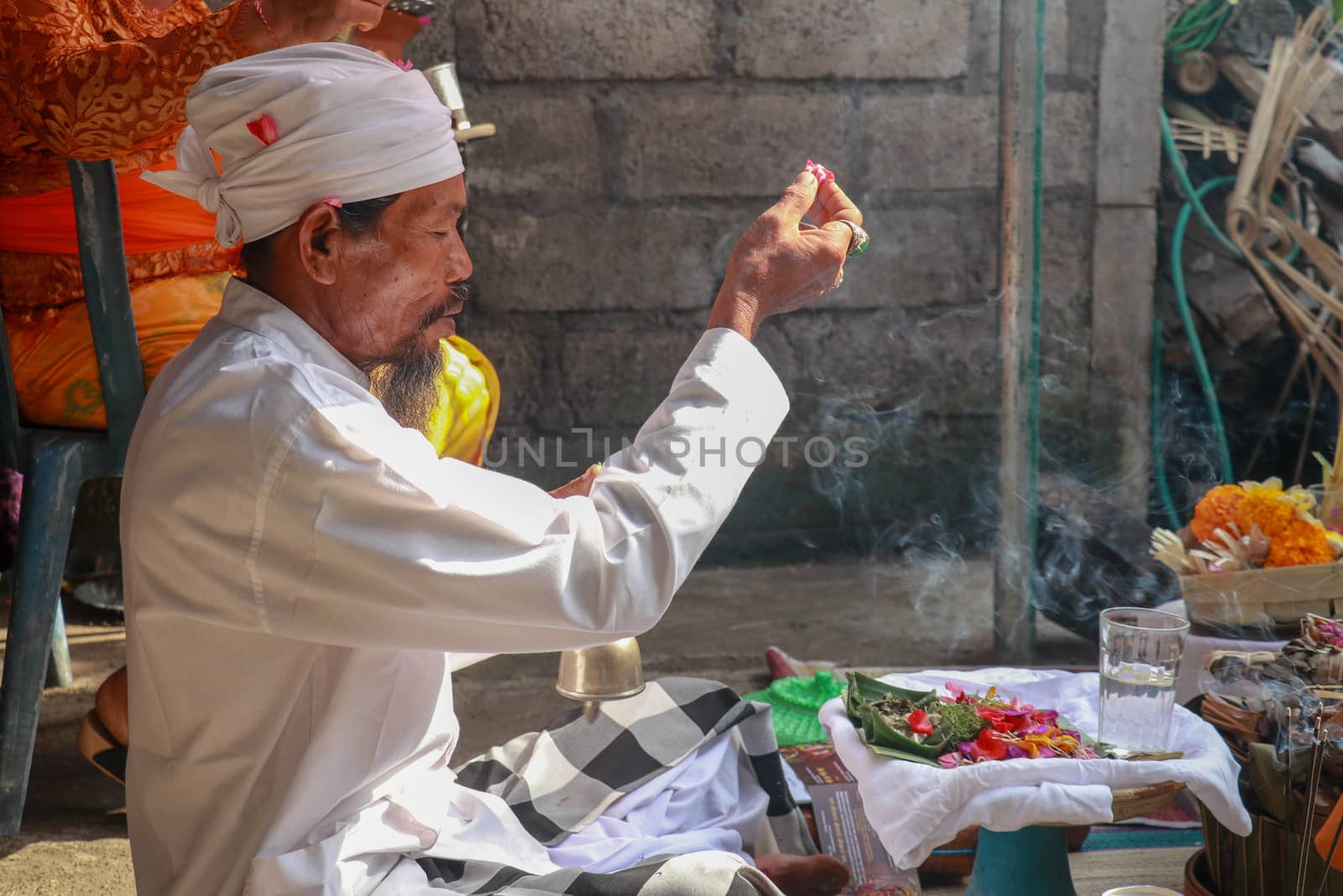 Close up of a Balinese pedanda during prayer. side view of a hindu priest performing a ceremony. A hindu priest performing offerings in a temple in Pemuteran in Bali, Indonesia by Sanatana2008