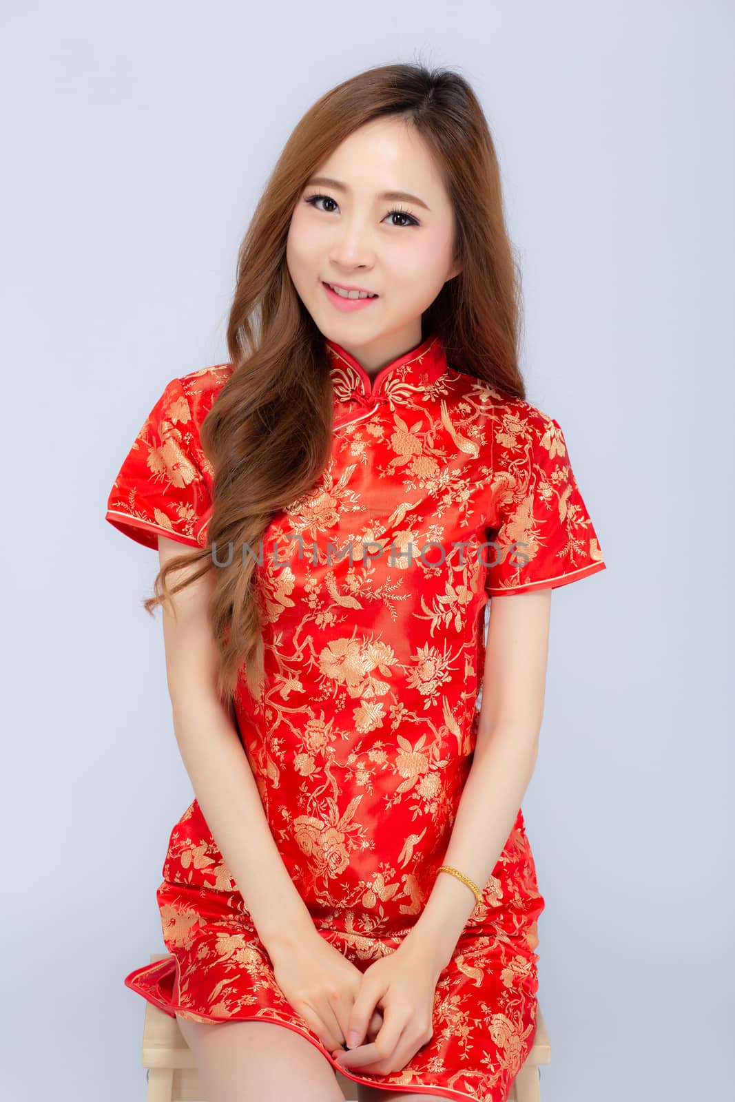 Beautiful portrait happy Chinese New Year young asian woman wear cheongsam smile with gesture congratulation and greeting isolated on white background, festival and celebrate concept.