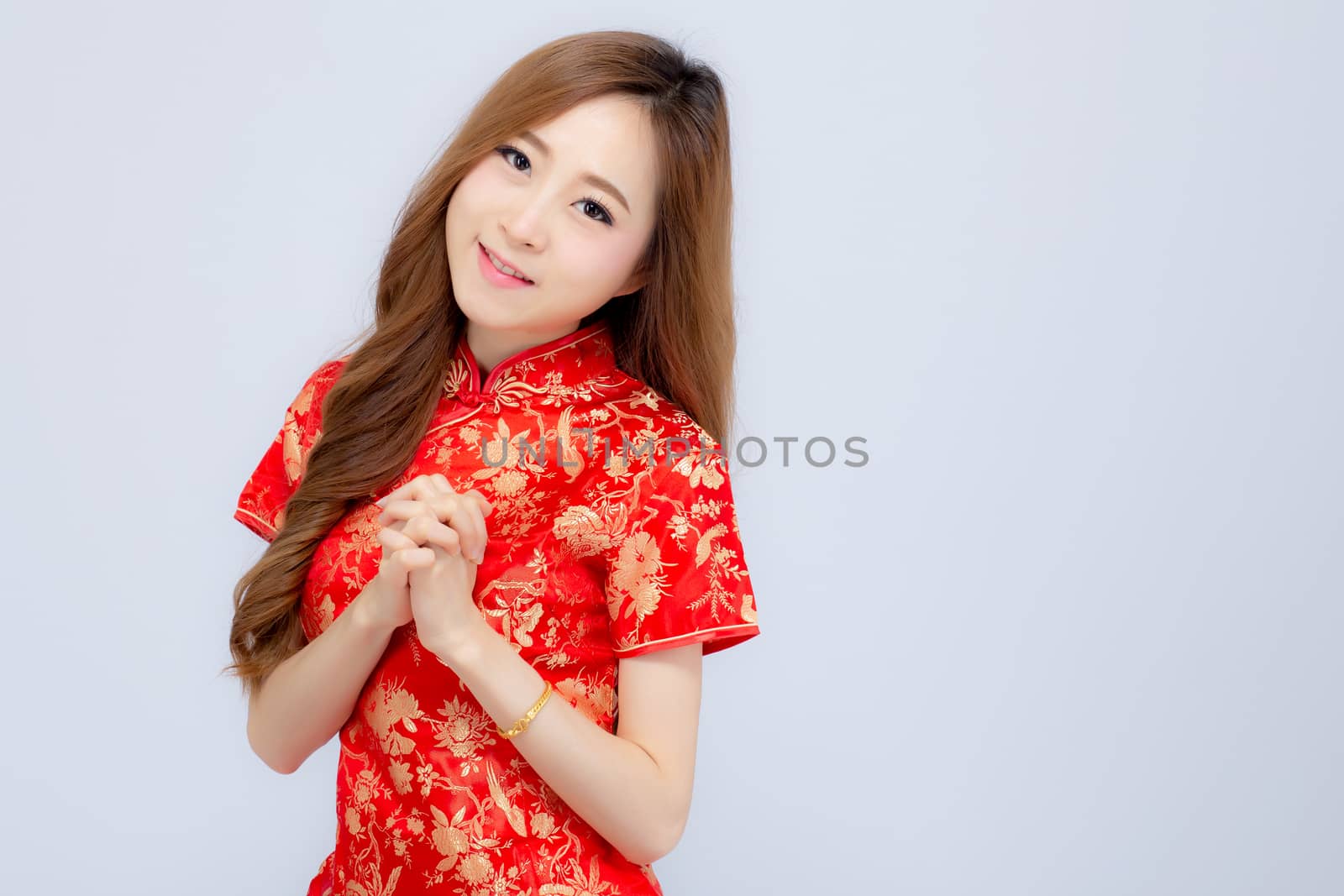 Beautiful portrait happy Chinese New Year young asian woman wear cheongsam smile with gesture congratulation and greeting isolated on white background, festival and celebrate concept.