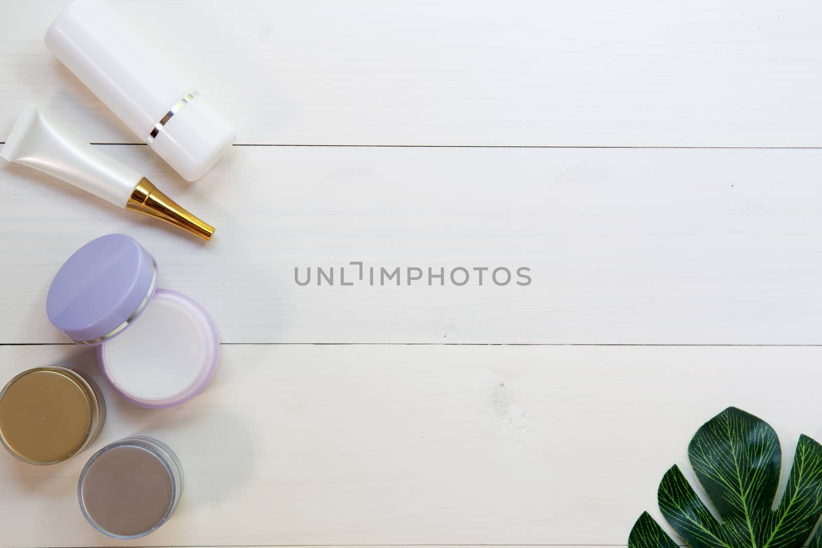 cosmetic and skin care product and green leaves on white wood table, beauty with treatment cream and moisturizing on wooden desk, health and wellness concept, top view.