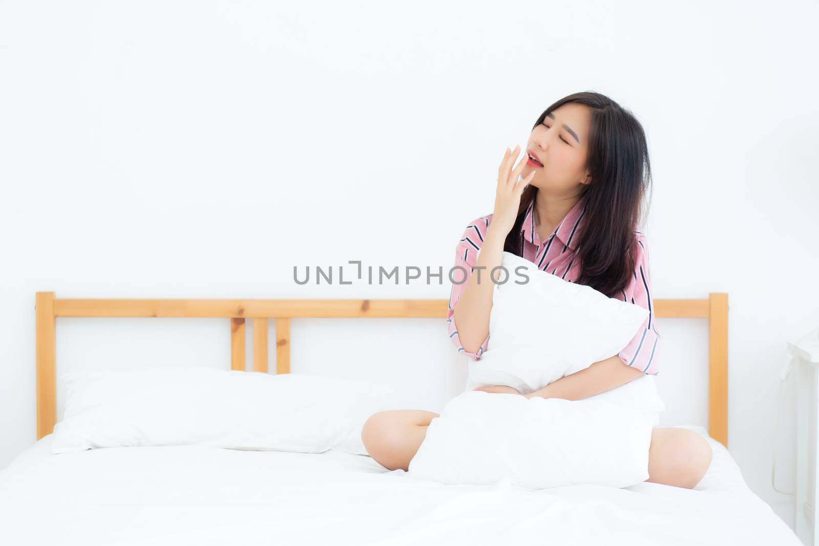 Beautiful of portrait young asian woman yawn sitting with sleep on bed at bedroom, girl wake up after resting and leisure with wellness, lifestyle concept.