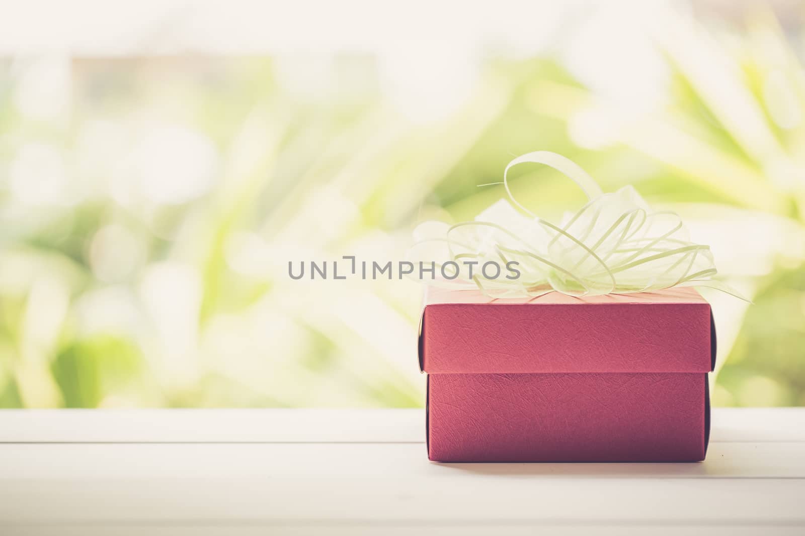 Holiday of Gift box with bow ribbon on wooden table, present of romantic day on wood nature background, Valentine festive concept, vintage retro tone.