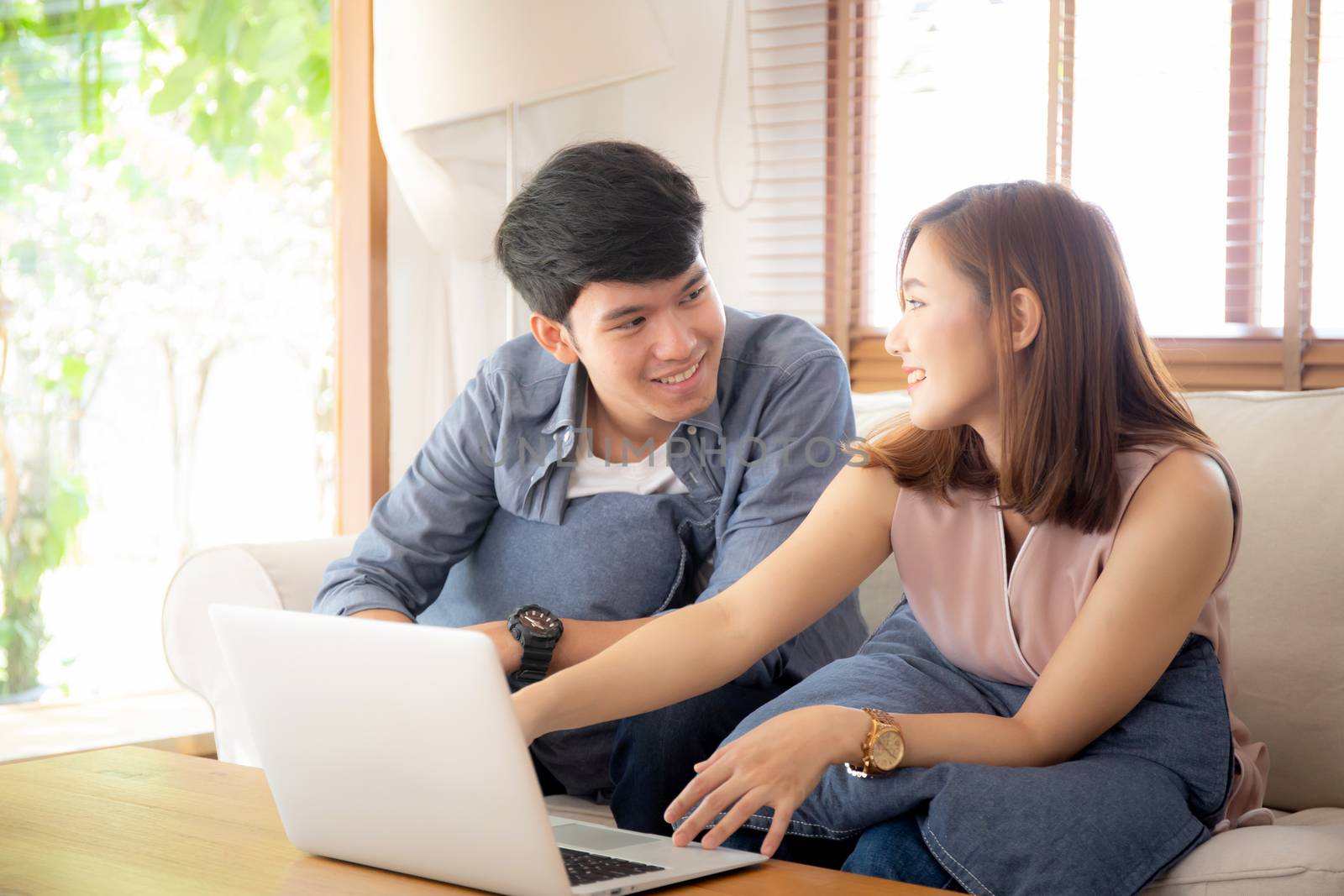 Asian young couple using laptop computer think and searching int by nnudoo