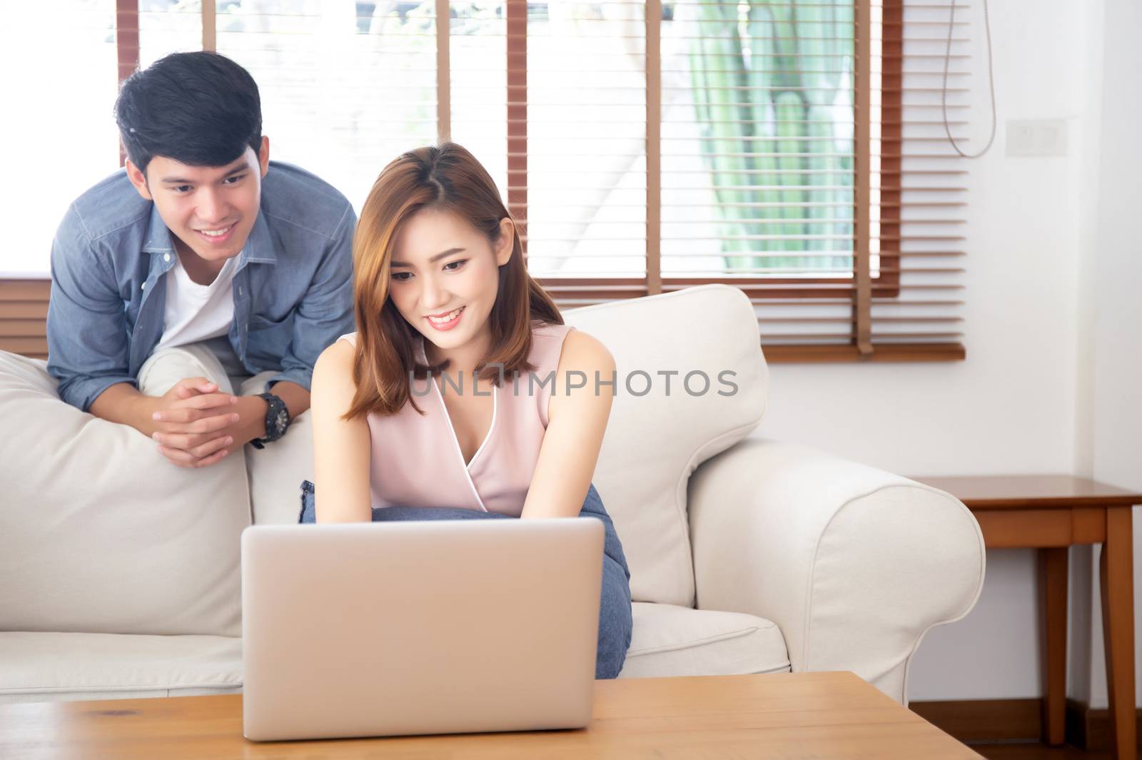 Asian young couple using laptop computer think and searching internet together, man and woman casual smiling work at home with happy and relax, communication and business concept.