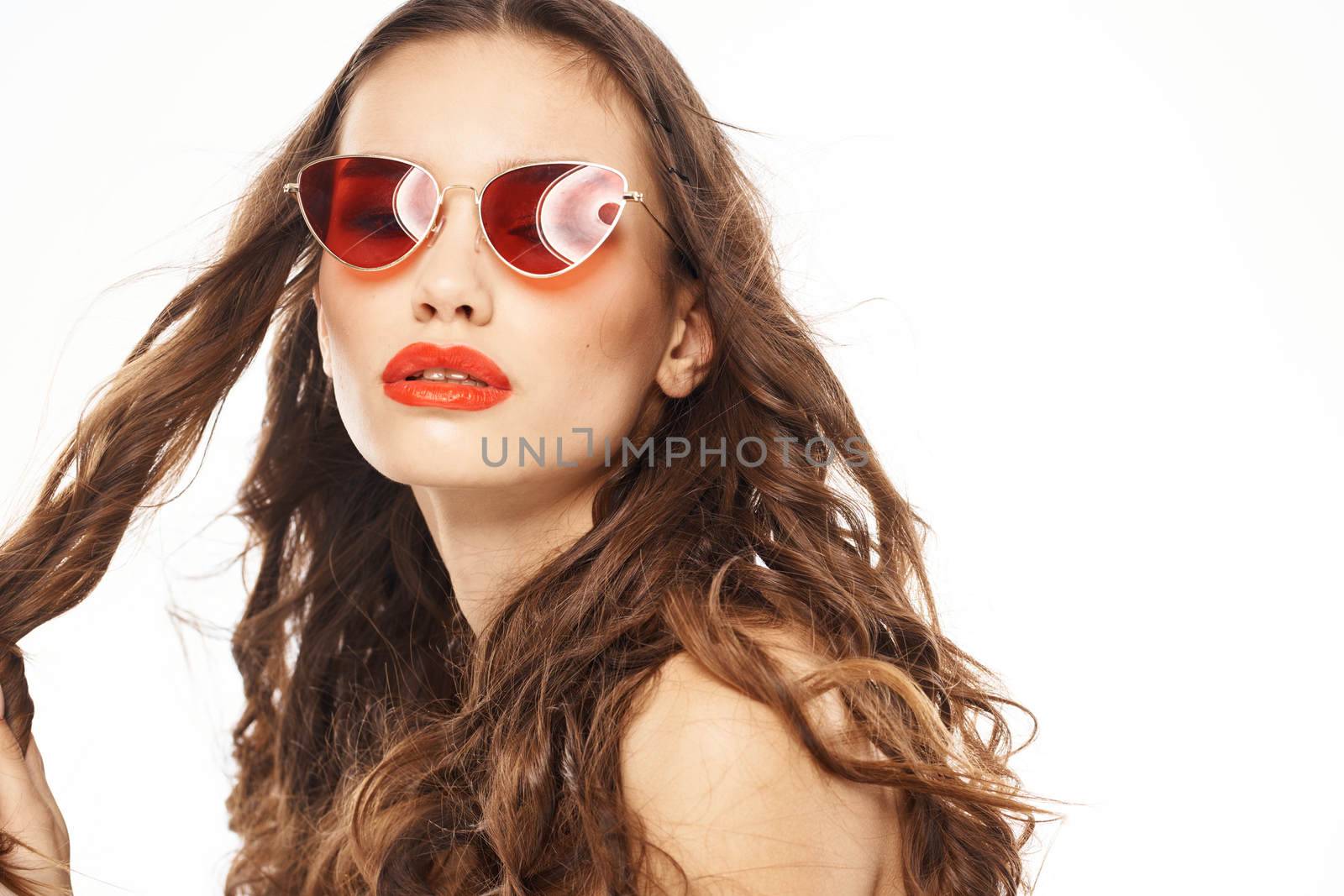 Portrait of brunette woman in sunglasses naked shoulders light background. High quality photo