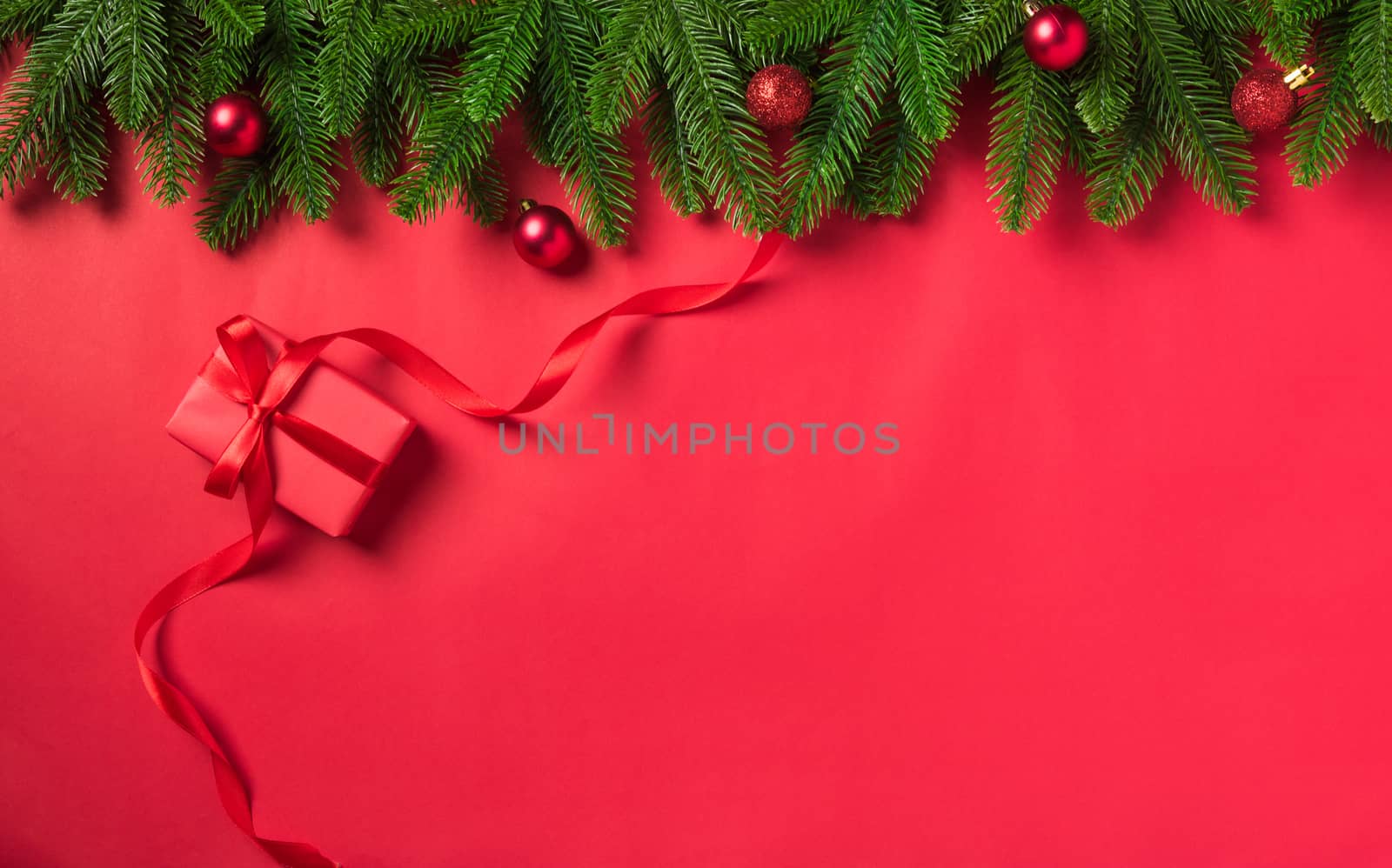 Christmas holiday background with gift box decorations composition, Top view fir green fir tree branches and Xmas ornaments on a red table background