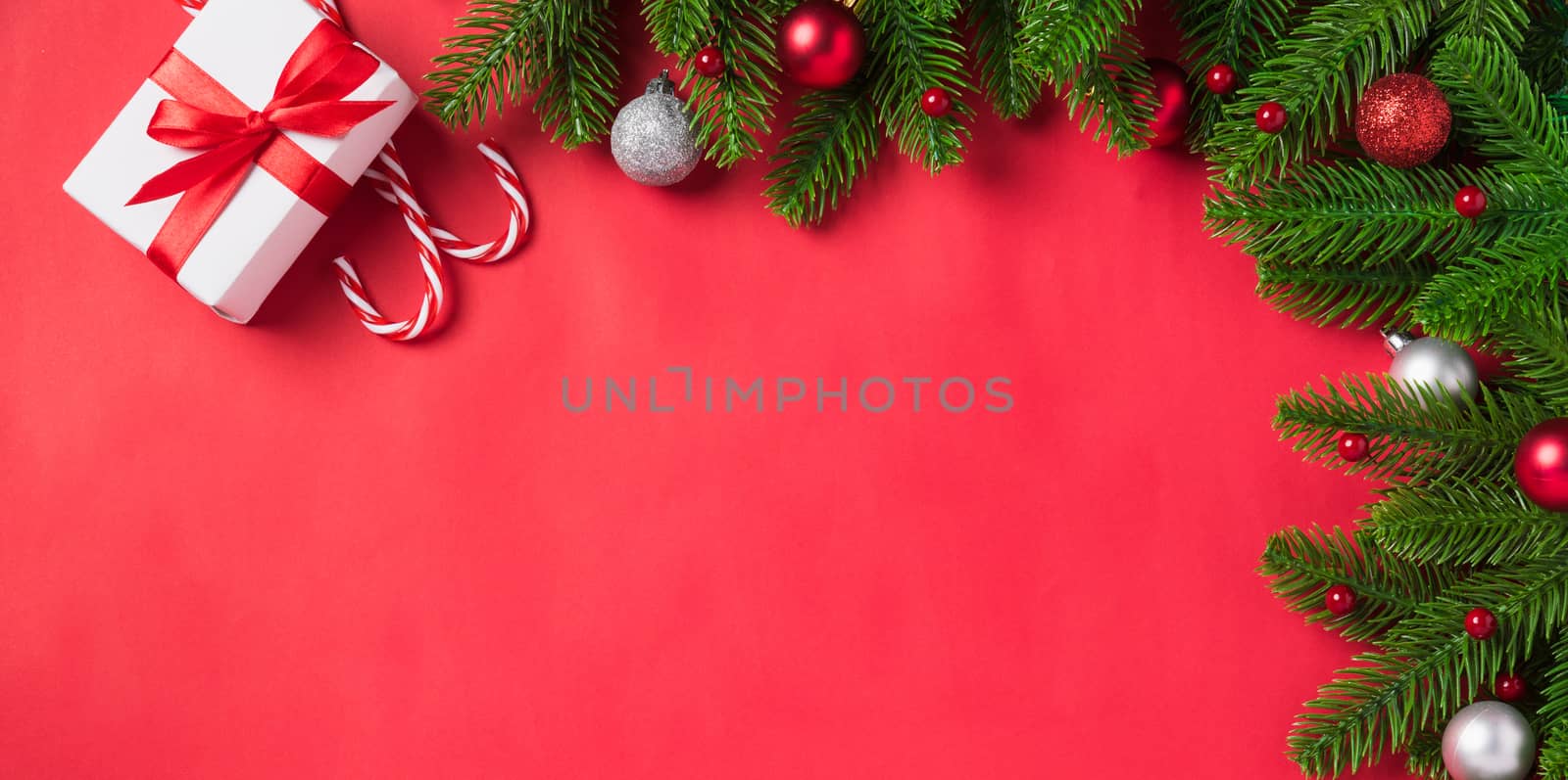 Christmas holiday background with gift box decorations composition, Top view fir green fir tree branches and Xmas ornaments gift box on a red table background, Happy New Year Day concept