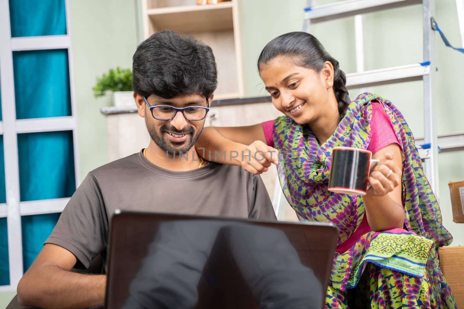 Couple at Newly bought apartment or house searching or planning for home improvement products on laptop while sitting together at unfurnished room