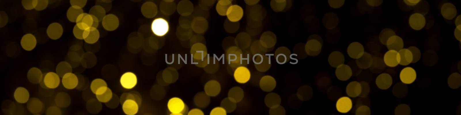 defocused gold christmas lights on dark background. yellow bokeh circles on black backdrop, christmas abstract background