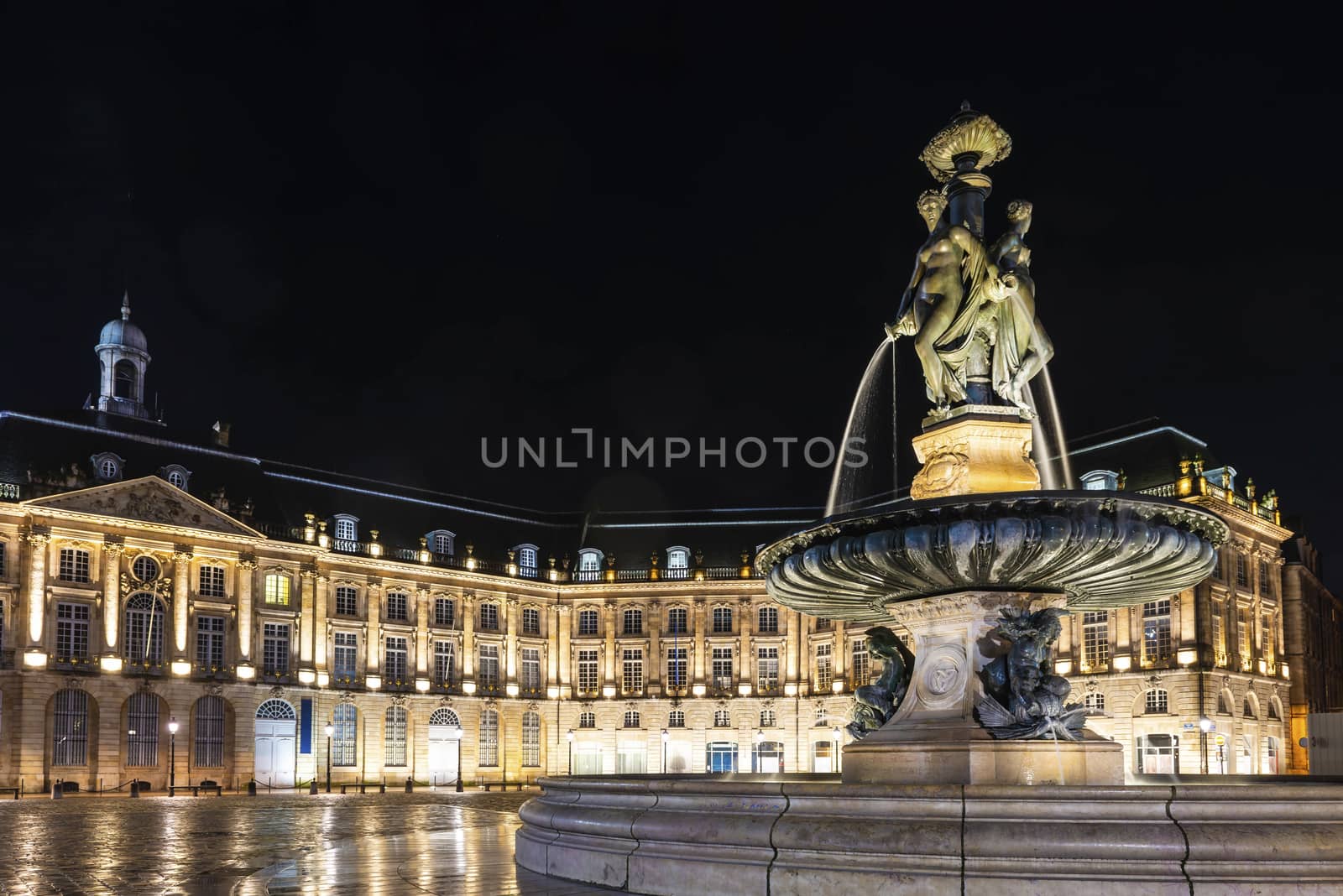 Place de la Bourse at night in Bordeaux, in the foreground, the fountain of the three grace and in the background the buildings of. by Frederic