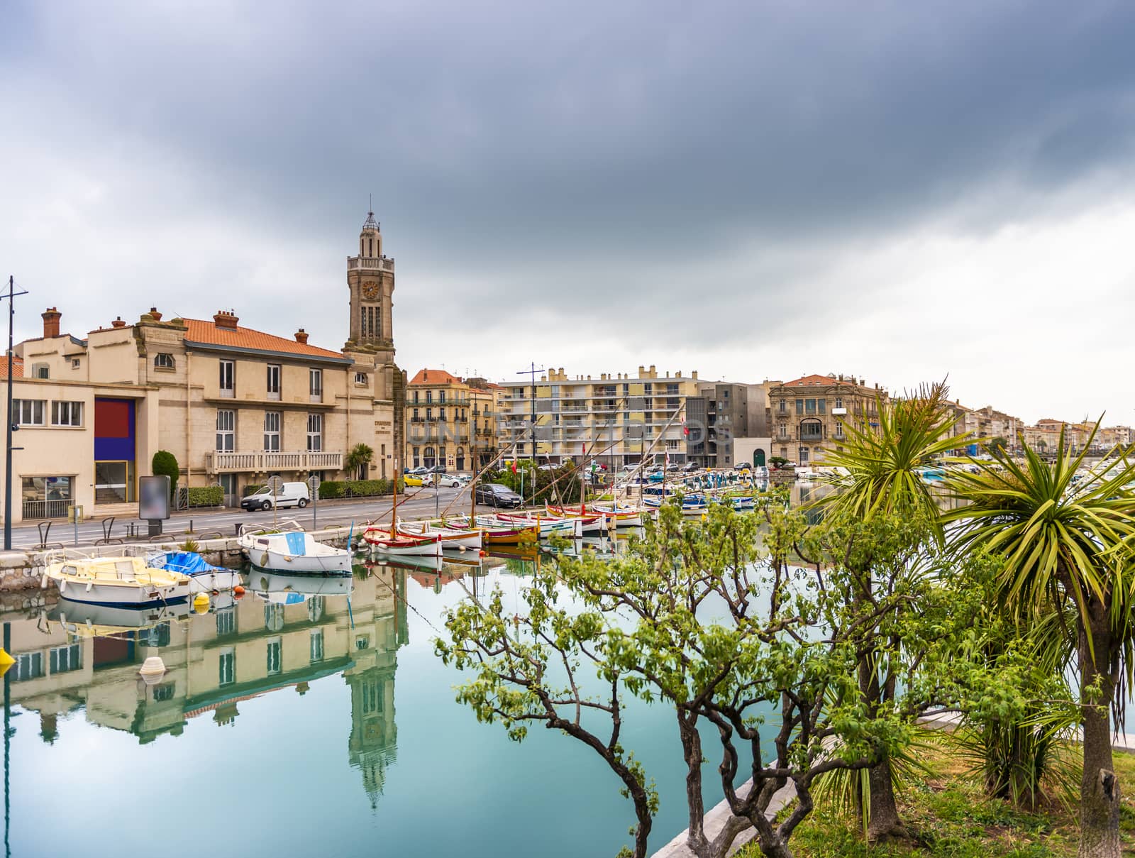 Reflections of the old chamber of commerce, on the royal canal in Sète under a very overcast sky. by Frederic