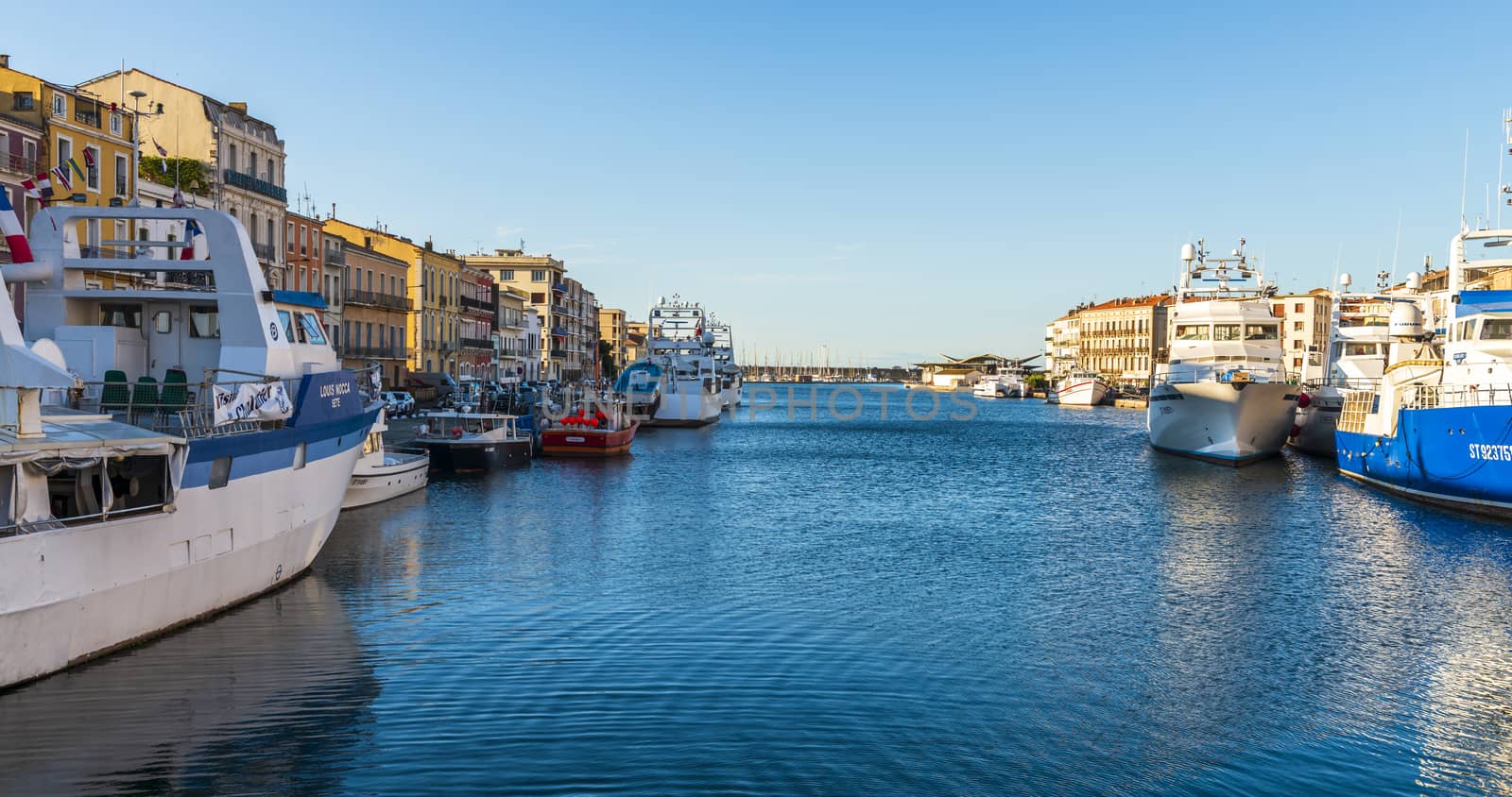 Sète Canal with its boats and trawlers, on a summer morning, in Sète in the Herault, inOccitania in France. by Frederic