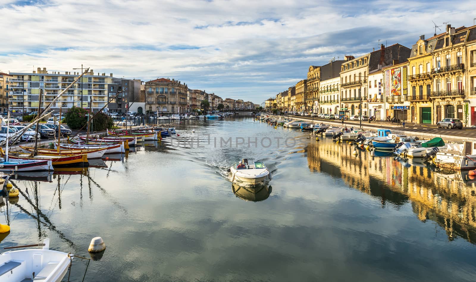 Panoramic view of the royal canal of Sète with a boat circulating, on a summer morning, in Hérault in Occitanie, France. by Frederic