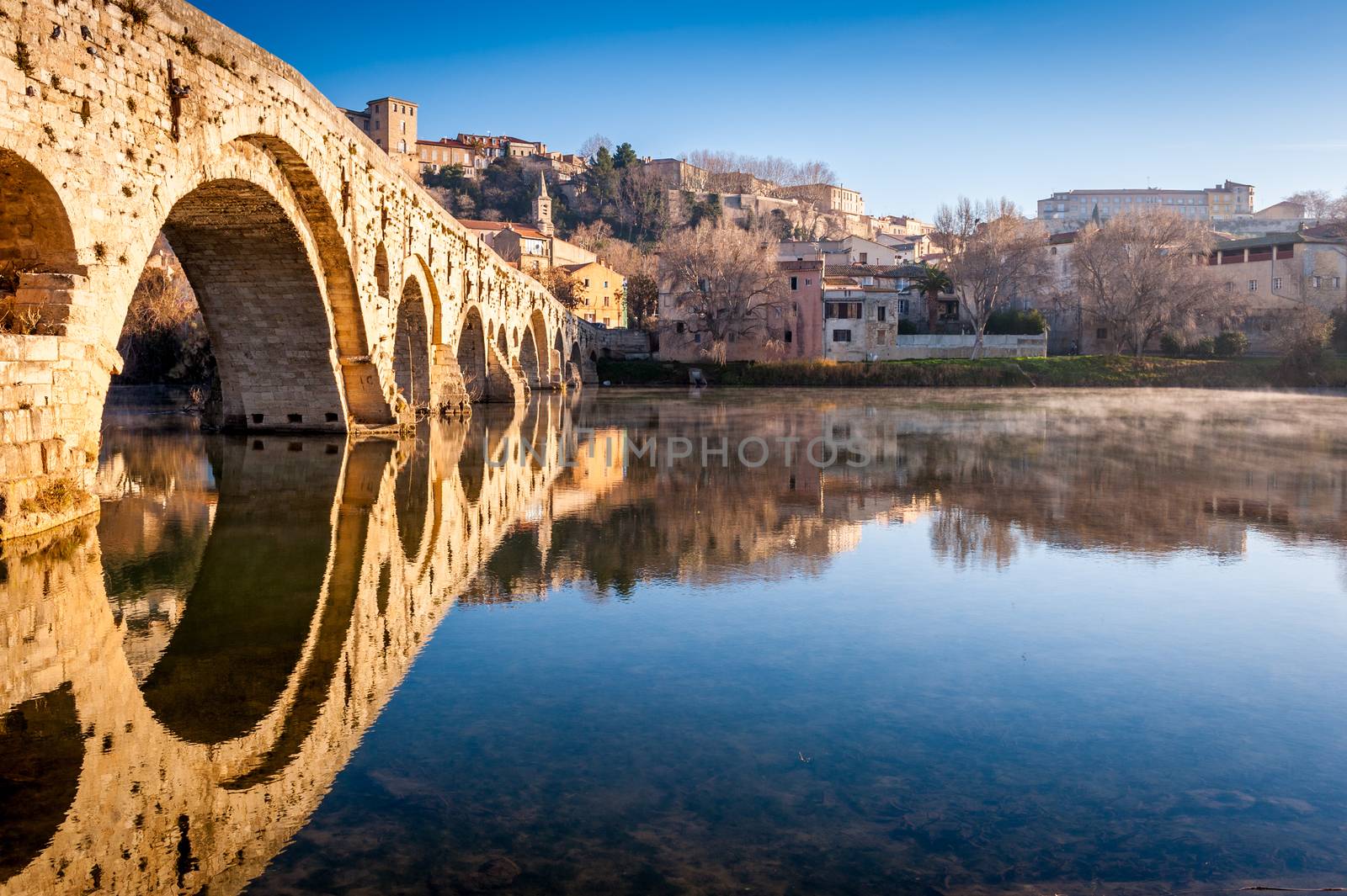 Perfect reflection worthy of a mirror, from the old bridge, on the calm water of the river Orb, one winter morning, at Béziers in the Hérault in Occitanie in the south of France