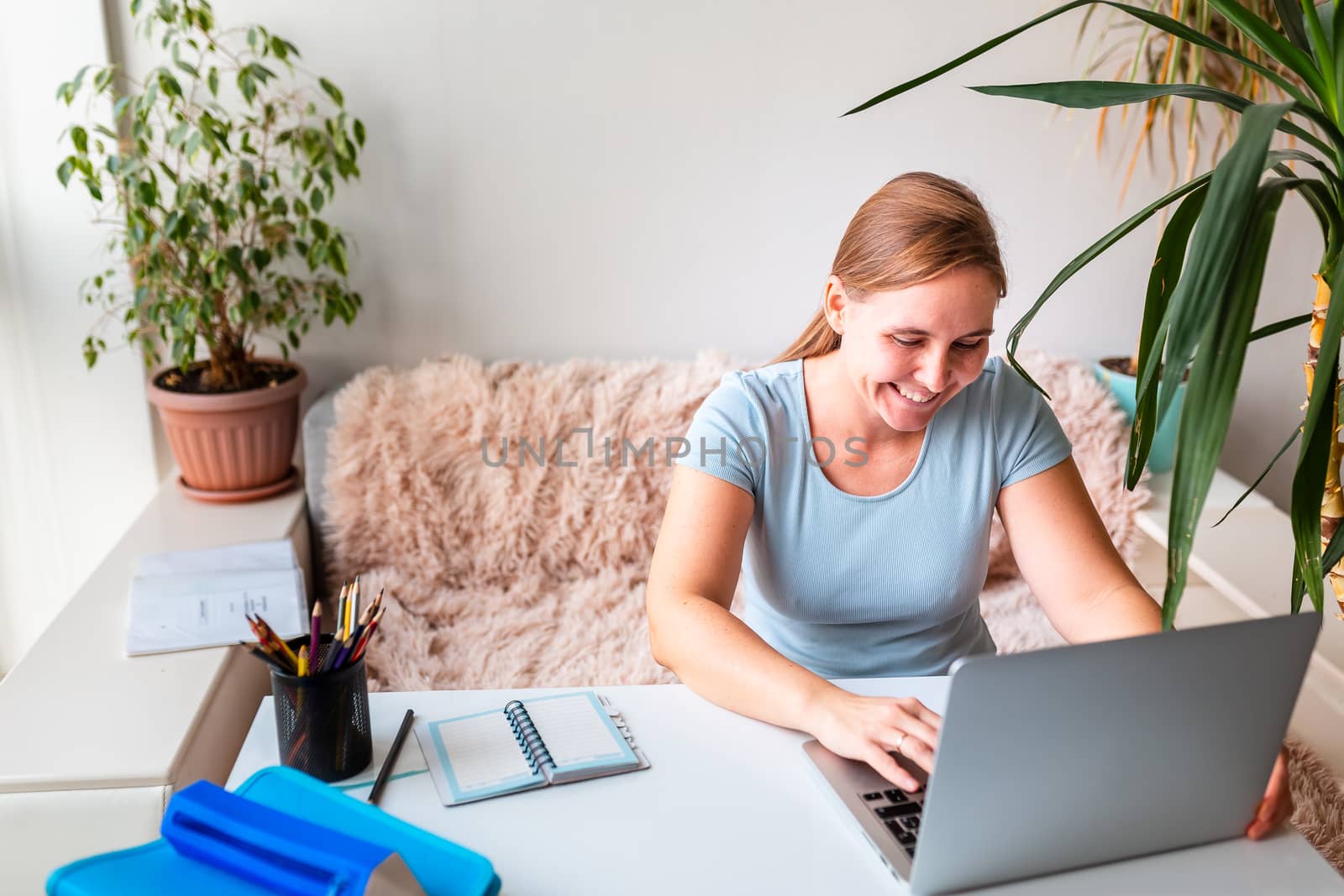 Middle age woman sitting at the table at home working using computer laptop. Work from home and stay at home during coronovirus pandemic concept