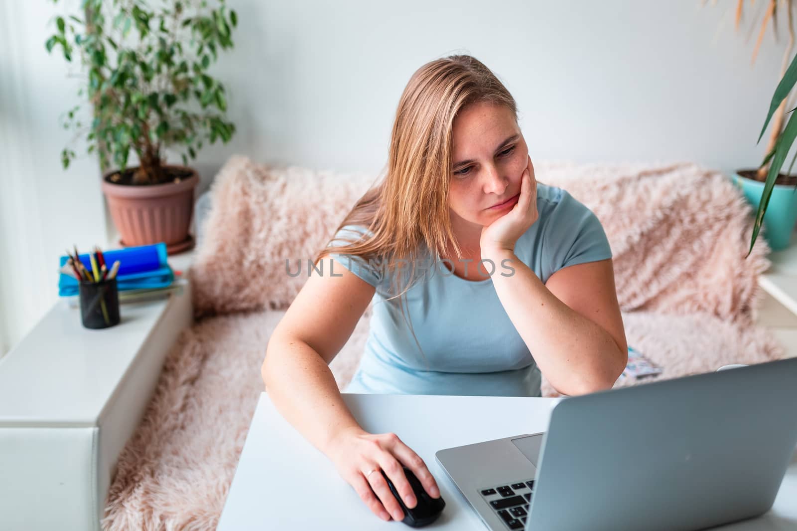 Middle age woman tired and bored sitting at the table at home working using computer laptop. Work from home and stay at home during coronovirus pandemic concept