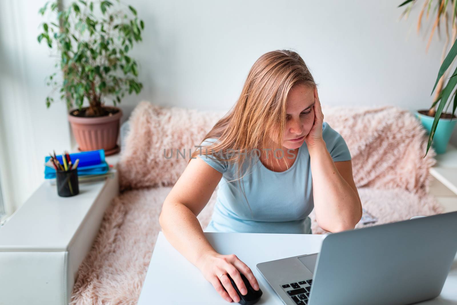 Middle age woman tired and bored sitting at the table at home working using computer laptop. Work from home and stay at home during coronovirus pandemic concept