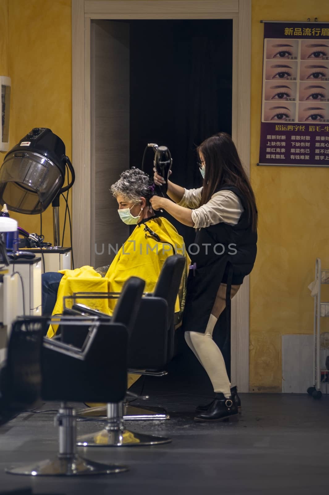 terni,italy september 02 2020:hairdresser who gives hair to a client with medical masks