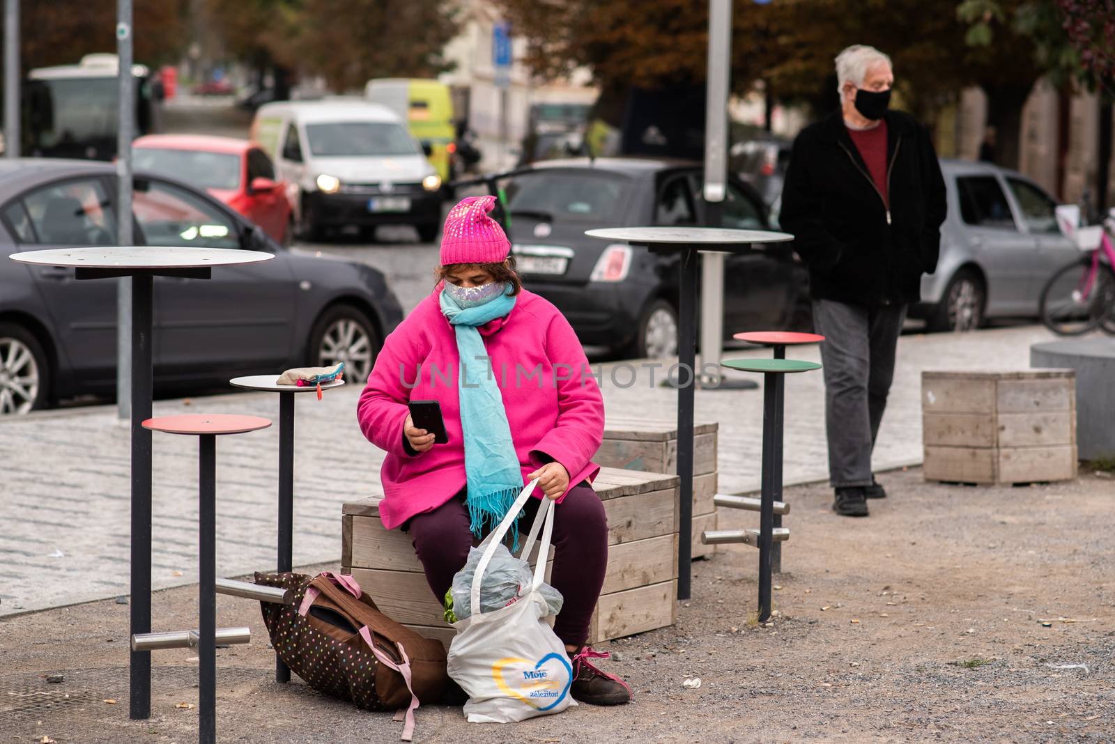 Woman carrying a mask resting with heavy bags during quarantine period due to outbreak of COVID-19 as winter is starting. Prague, Czech Republic
