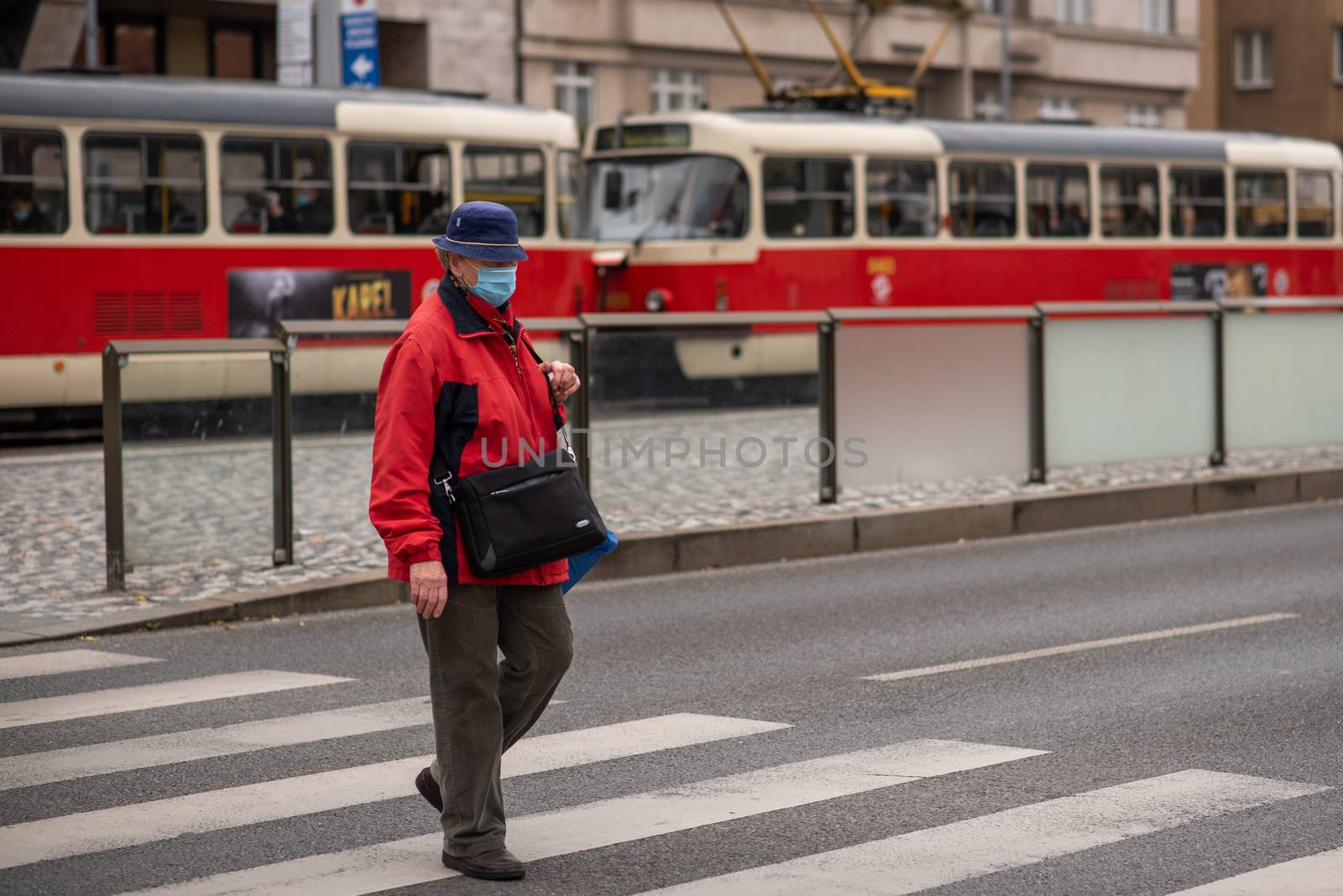 Woman with mask is crossing the street at Hradcanska metro station during quarantine period due to outbreak of COVID-19 as winter is starting. Prague, Czech Republic