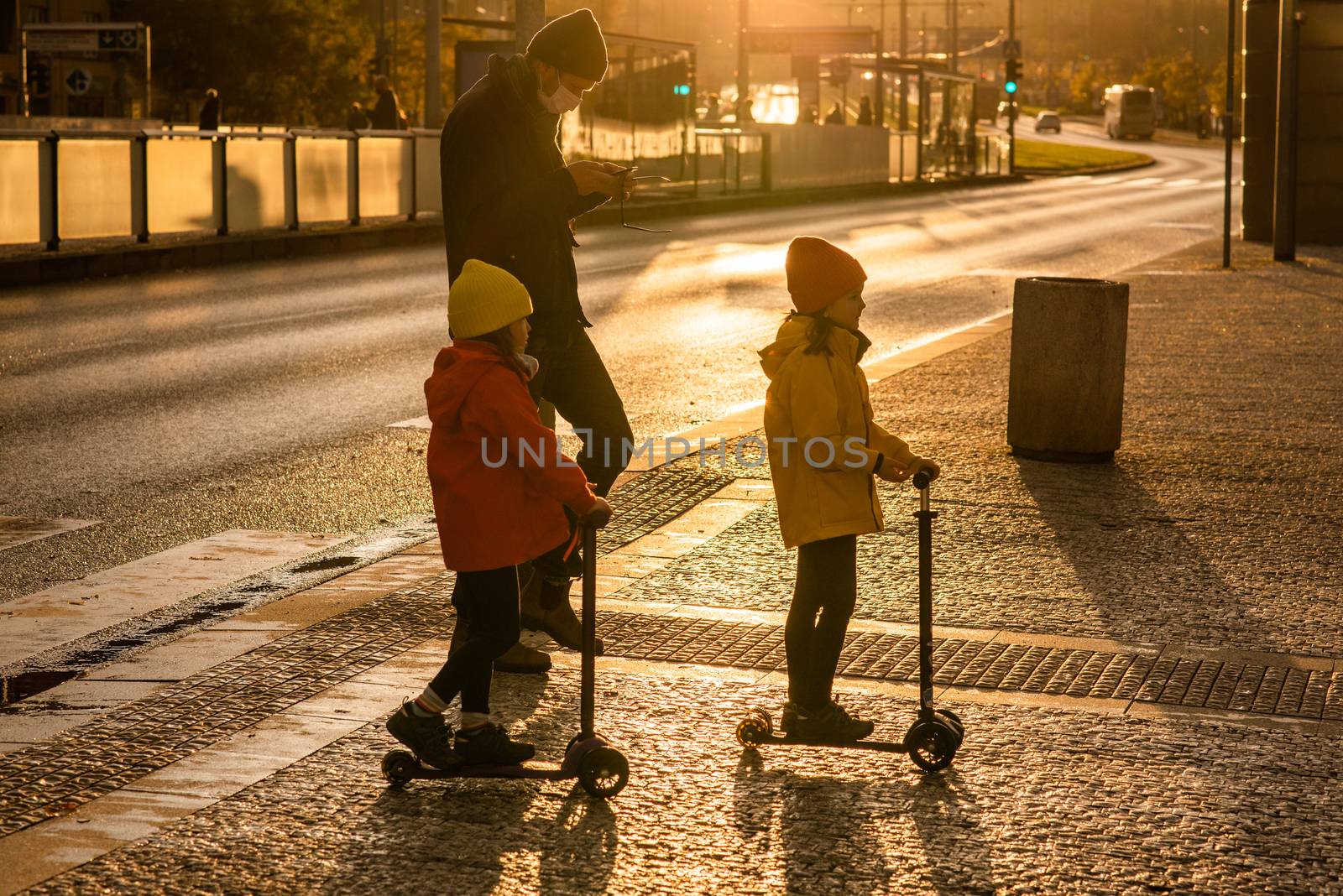 20/10/2020. Prague, Czech Republic. Father and two daughters with mask are crossing the street at Hradcanska metro station with scooters during quarantine period due to outbreak of COVID-19 as winter is starting. Prague, Czech Republic by gonzalobell