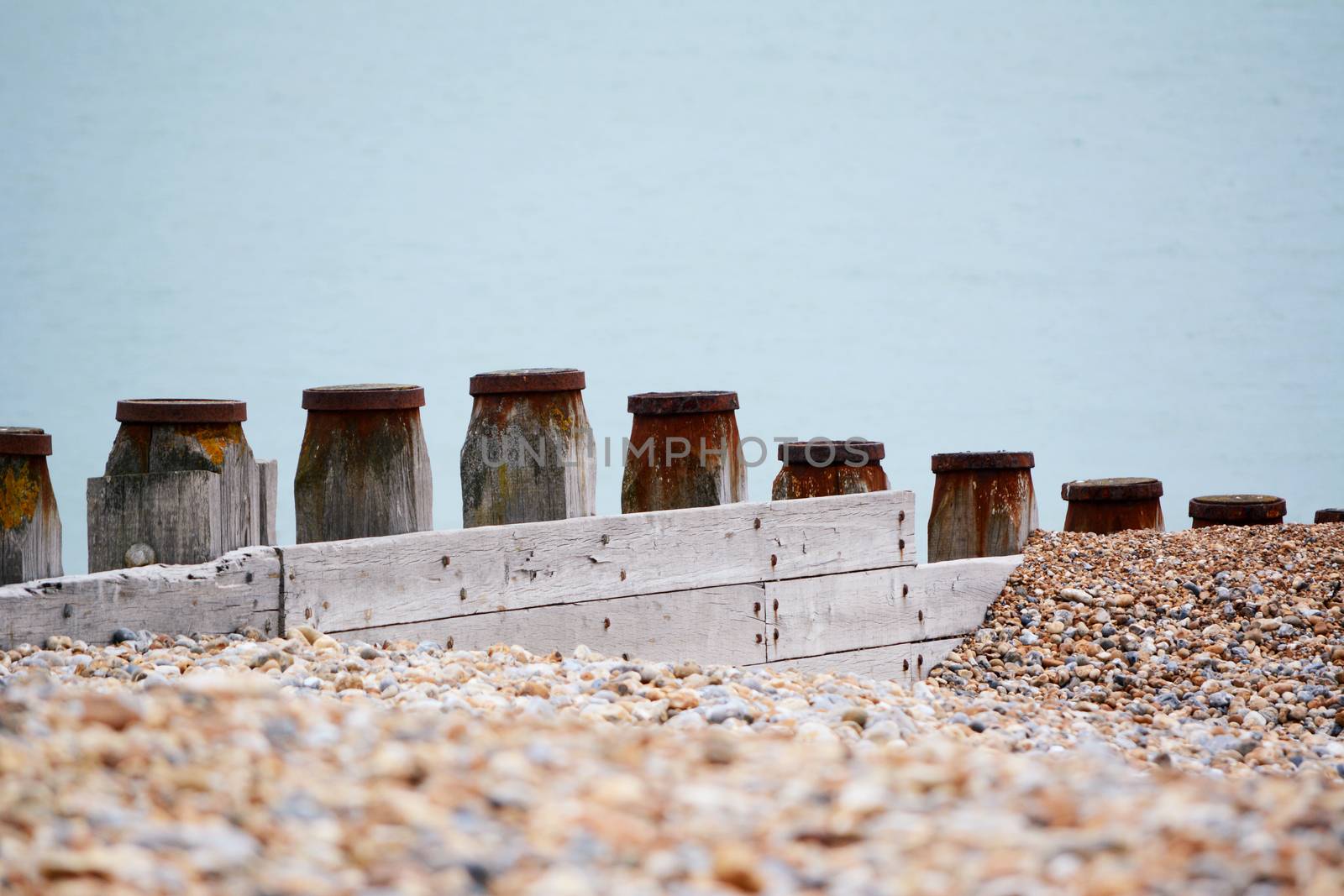 Wooden groynes form sea defences to prevent coastal erosion on shingle beach in Eastbourne, East Sussex