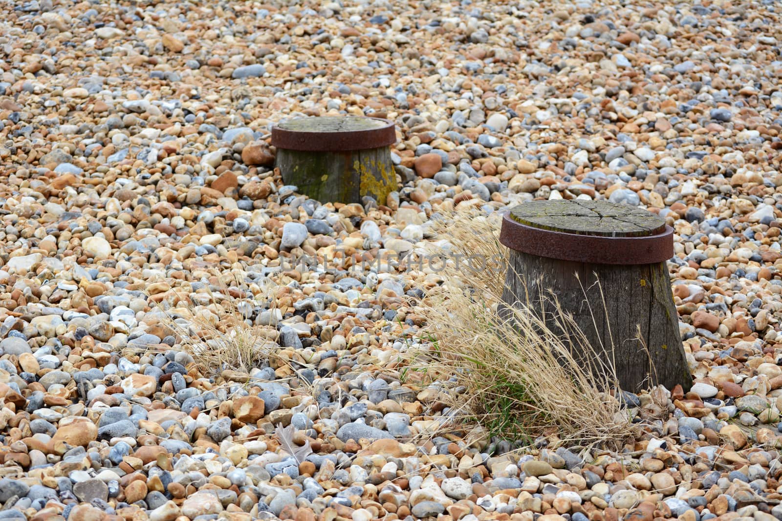 Tops of two groyne sea defences visible on a shingle beach by sarahdoow