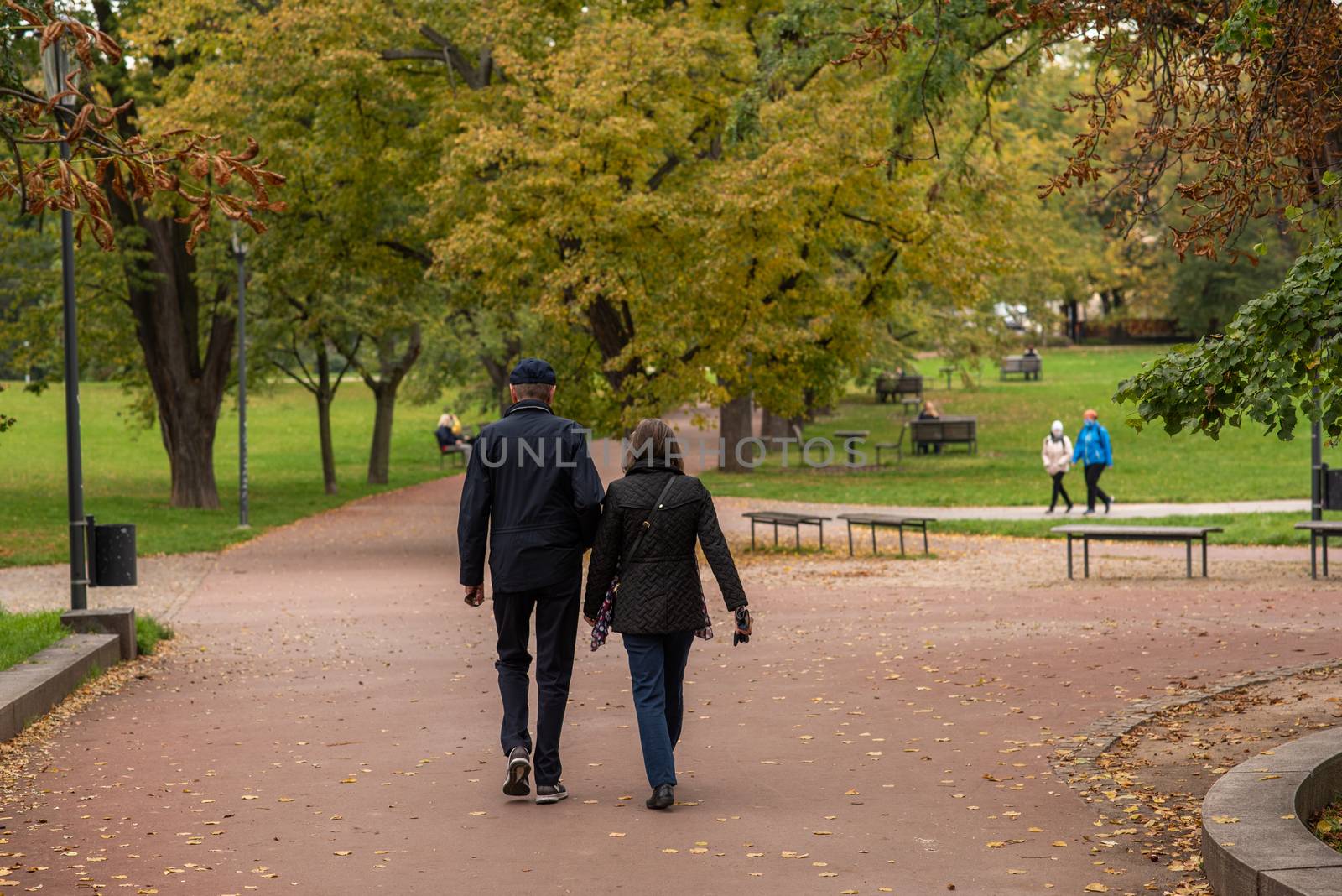 Man and woman are walking and talking on Letna Park in Autumn 2020 on Prague 6, during quarantine period due to outbreak of COVID-19 as winter is starting, Czech Republic by gonzalobell