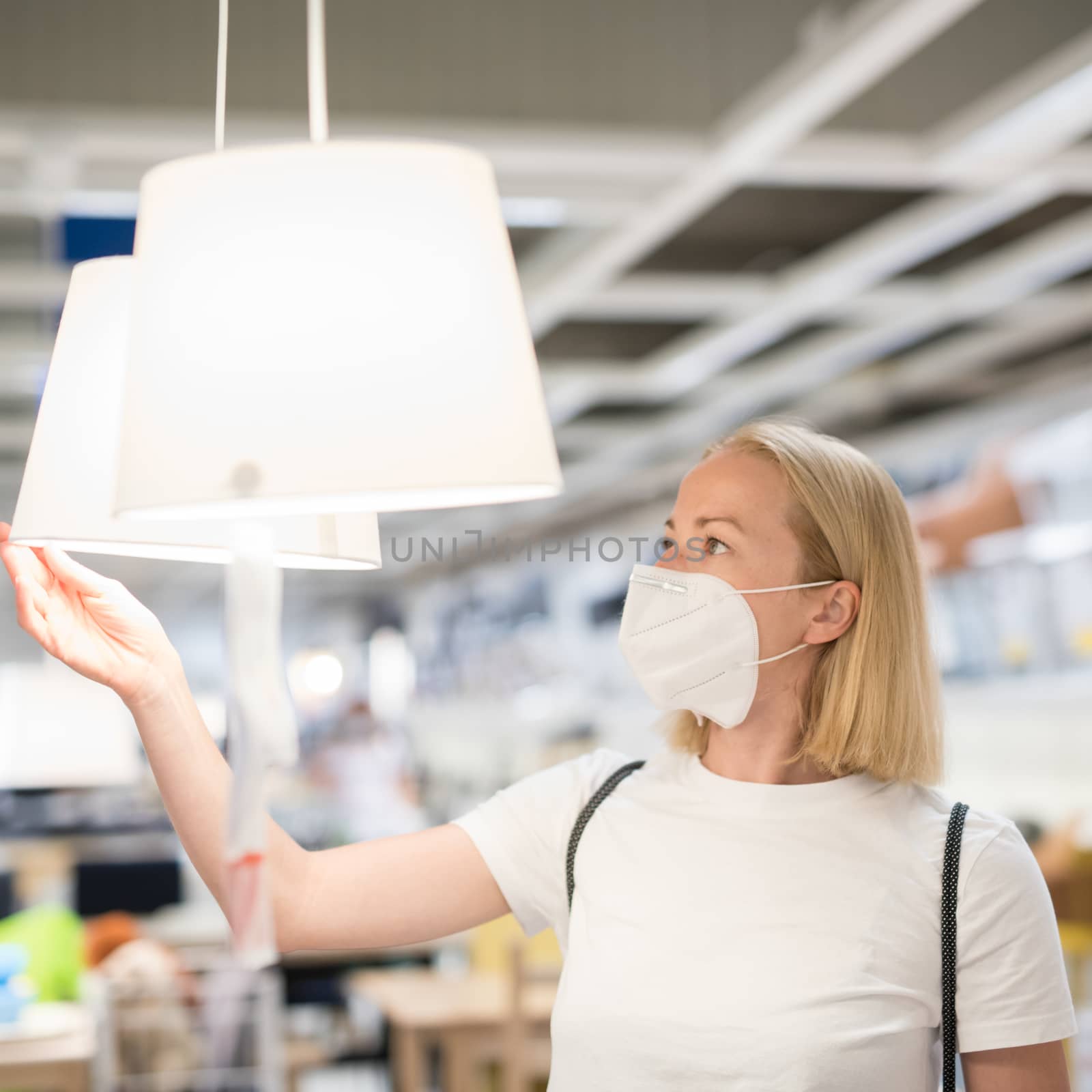 New normal during covid epidemic. Caucasian woman shopping at retail furniture and home accessories store wearing protective medical face mask to prevent spreading of corona virus by kasto