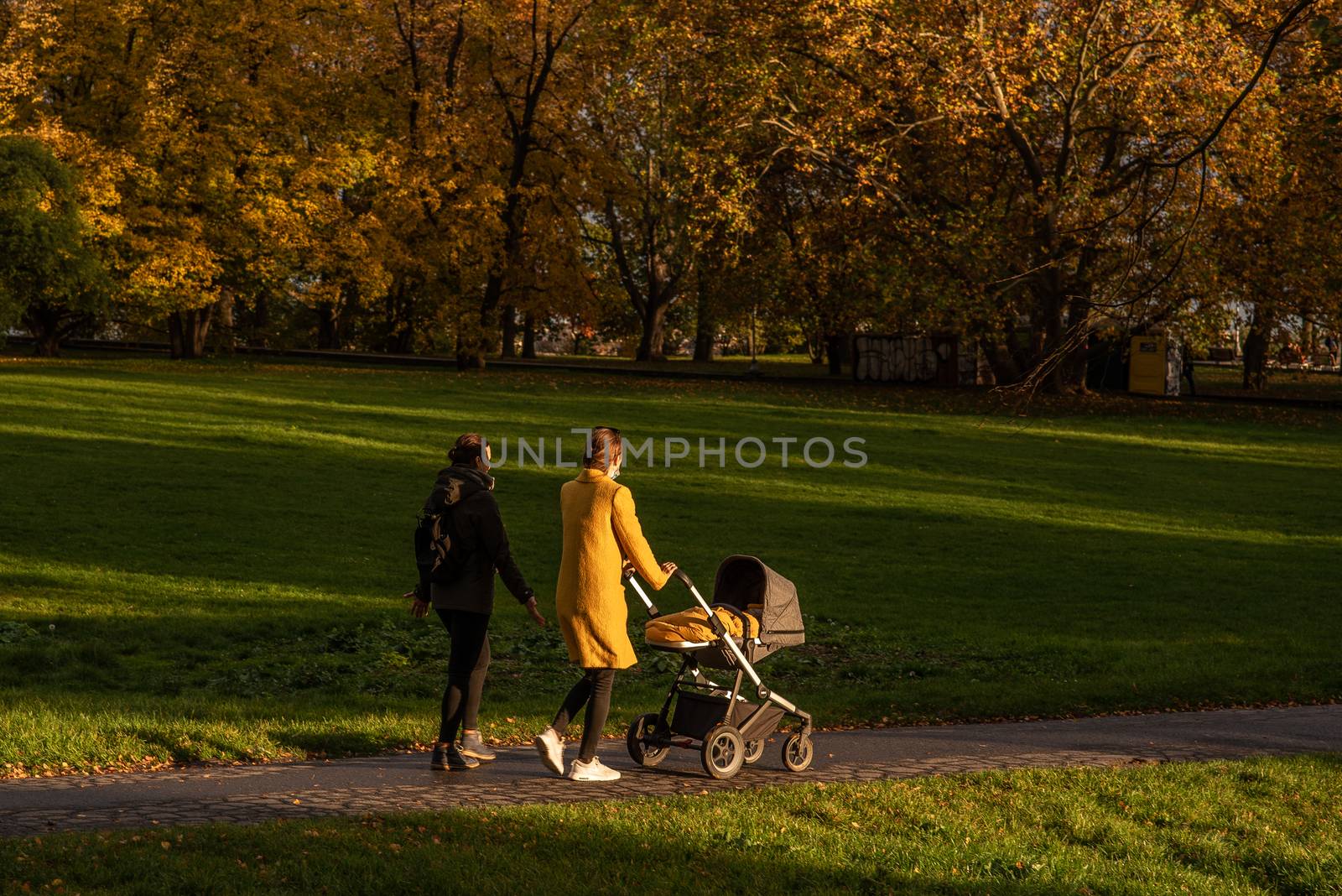 Two woman (one carrying a baby stroll) are enjoying a walk Autumn 2020 on Prague 6, during quarantine period due to outbreak of COVID-19 as winter is starting, Czech Republic