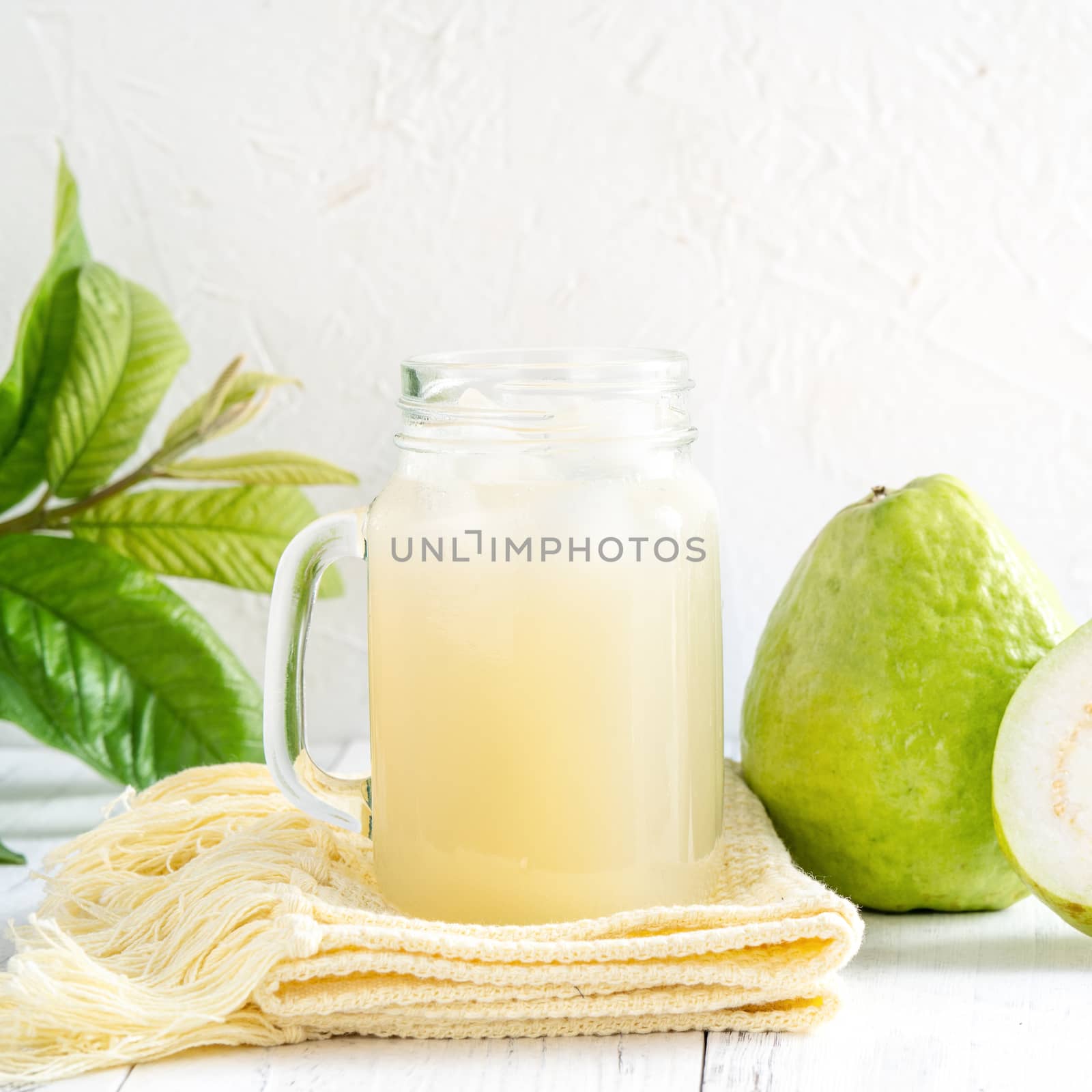 Delicious beautiful guava fruit with fresh juice set isolated on bright white wooden table background, close up.