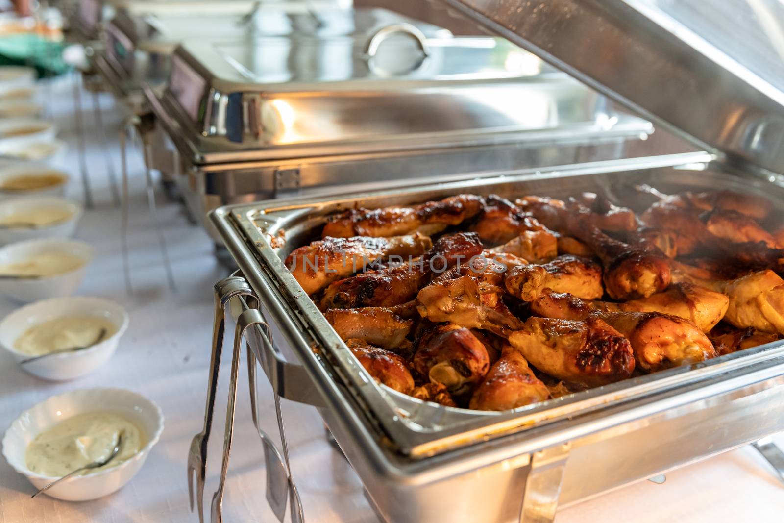 roast chicken thighs in a warming pot on a catering table.
