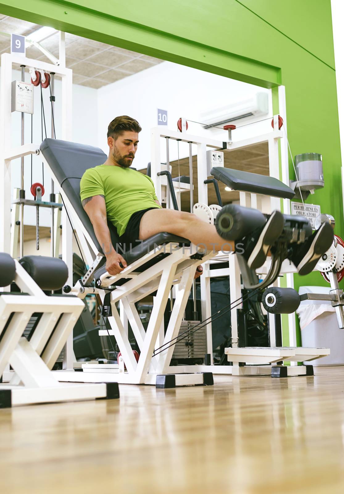 Young sportsman almost shouting when doing leg extension with heavy weight