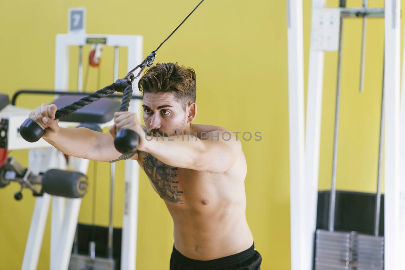 Fit man on lat pull down machine at the health club. Work out on Pull down Weight Machine