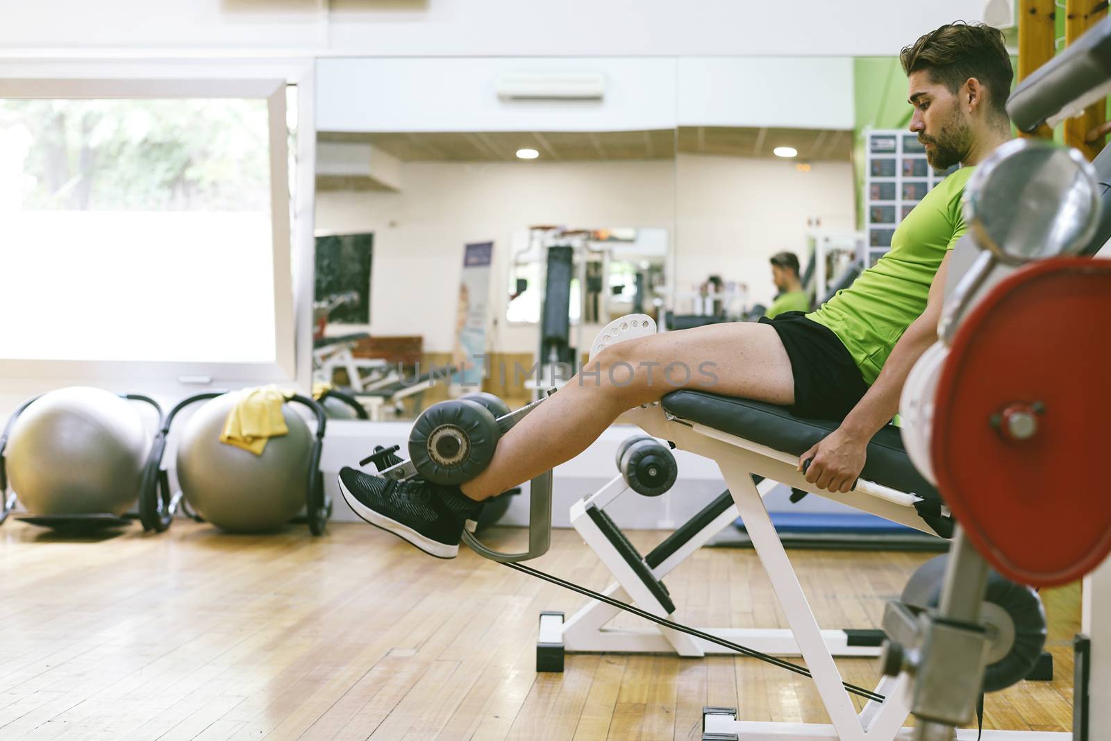 Young sportsman almost shouting when doing leg extension with heavy weight