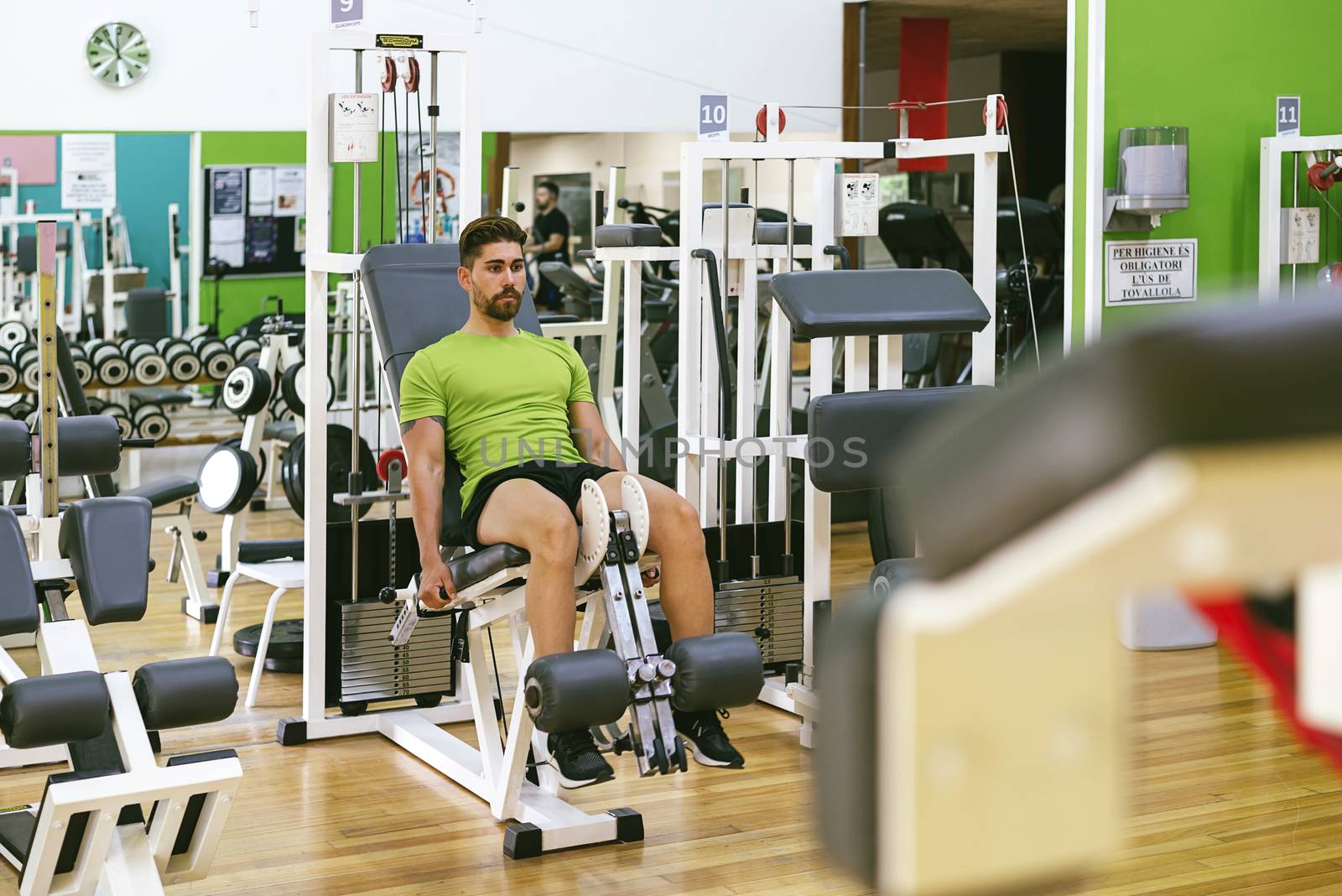 Young sportsman almost shouting when doing leg extension with heavy weight