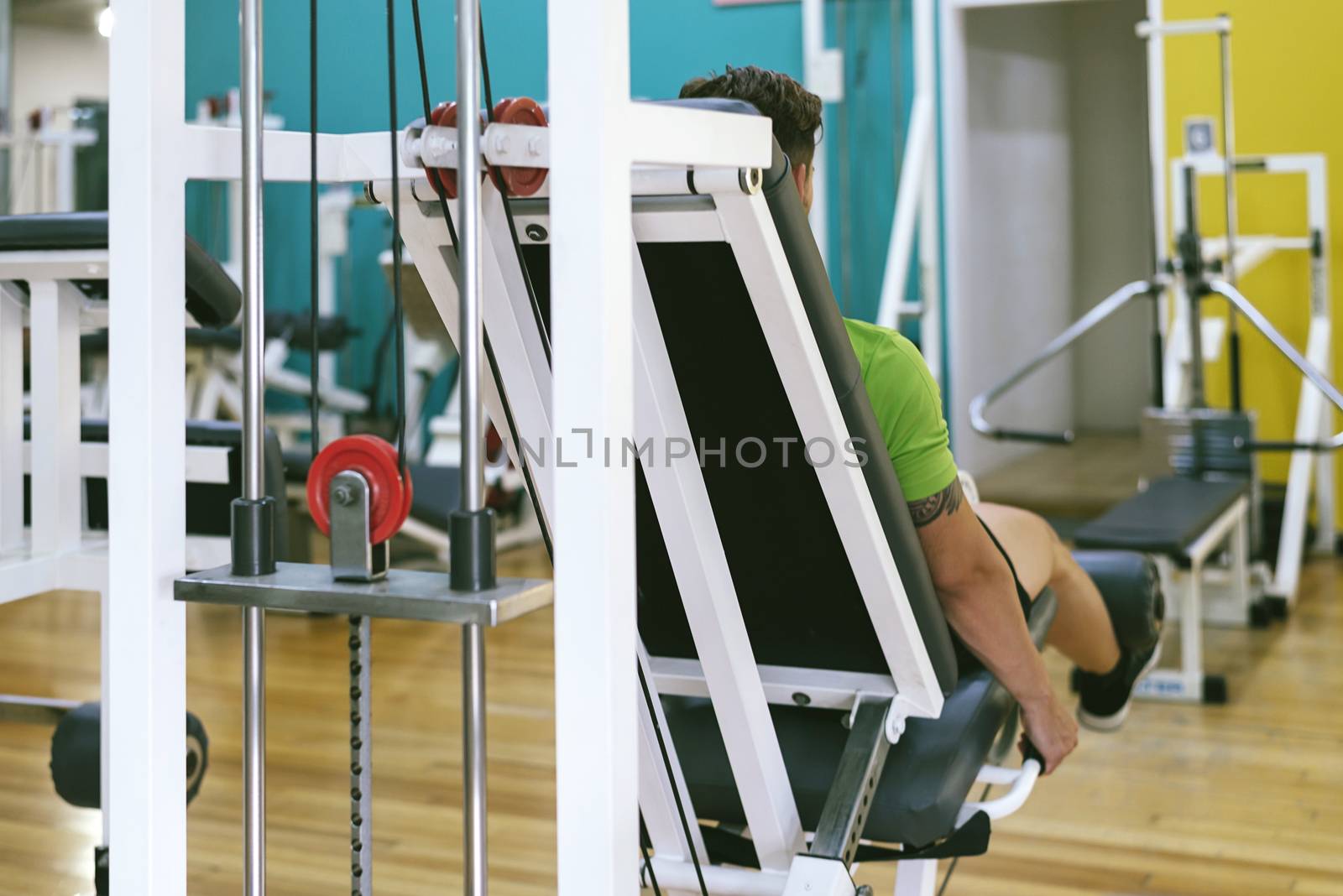 Young sportsman almost shouting when doing leg extension with heavy weight