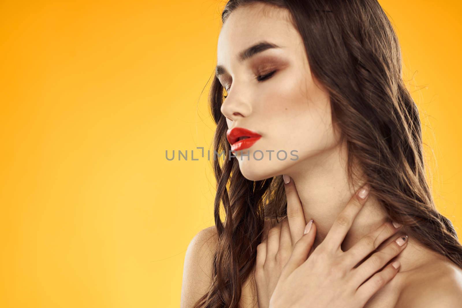 Beautiful brunette naked shoulders bright makeup red lips hairstyle close-up yellow background by SHOTPRIME