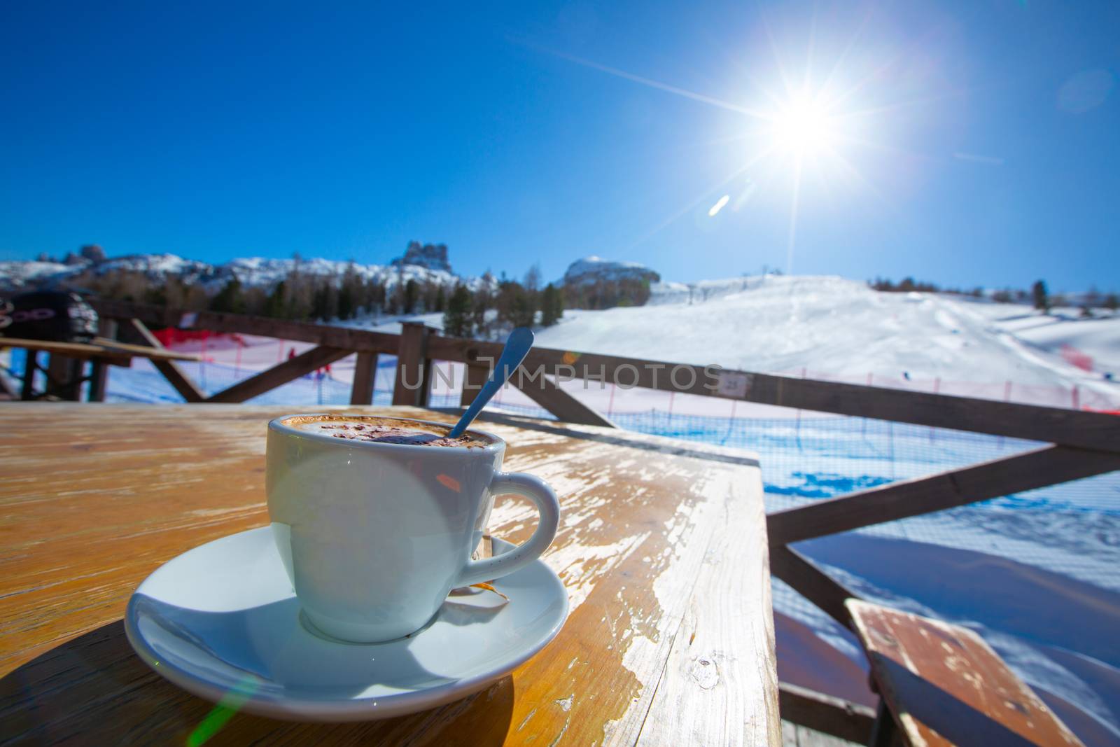 Cup of Cappuccino coffee on table in cafe at ski resort in Italy Dolomites alps