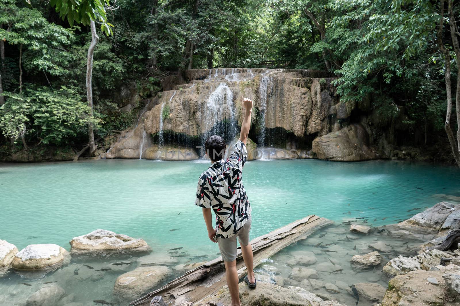 Man standing on the stone at Erawan waterfall at National Park, Kanchanaburi, Thailand.