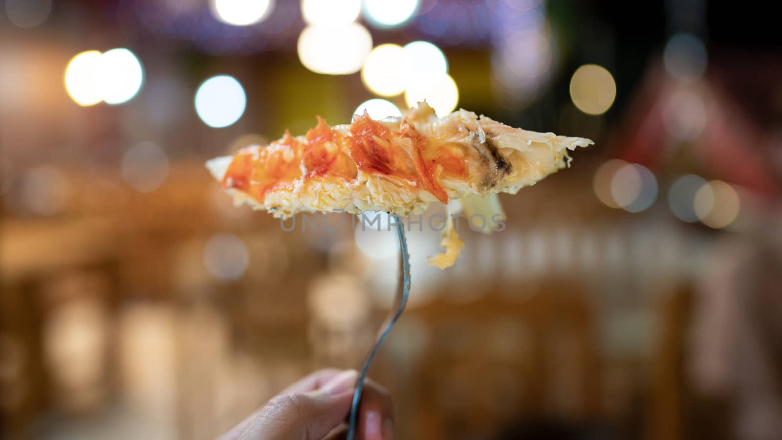 Peeled shrimp on a fork on blurred background.