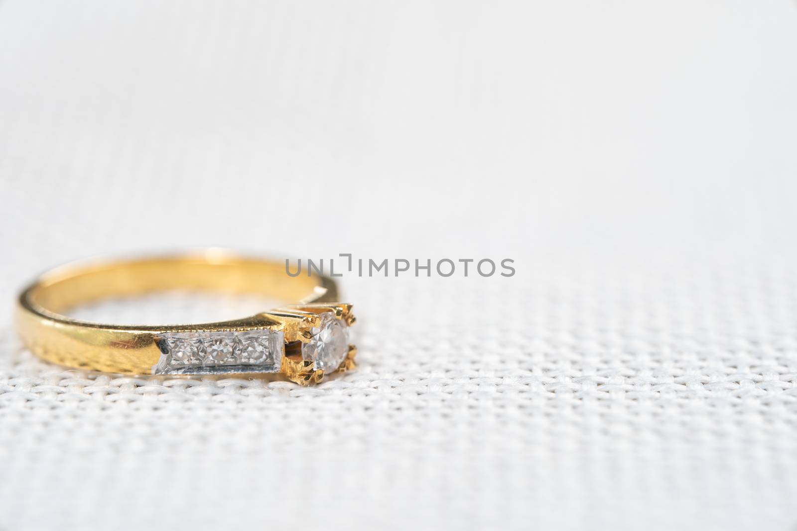 Minimal wedding diamond ring on white sack background.