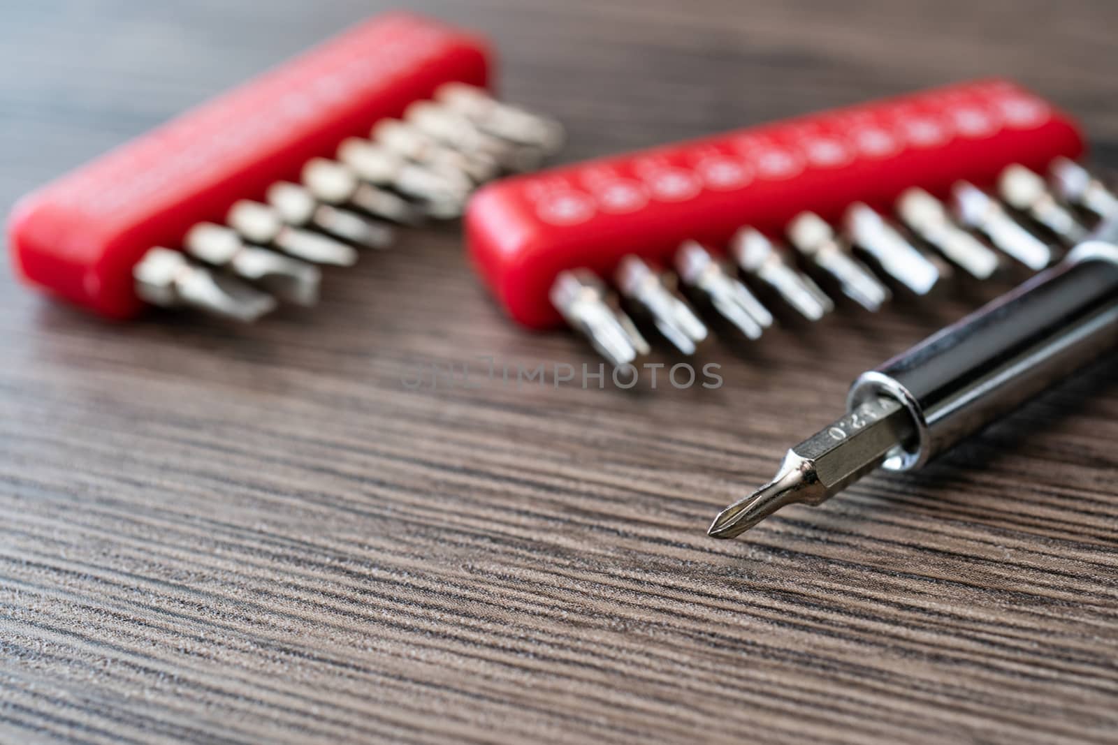 Set of heads for screwdriver, tools collection on wooden table.