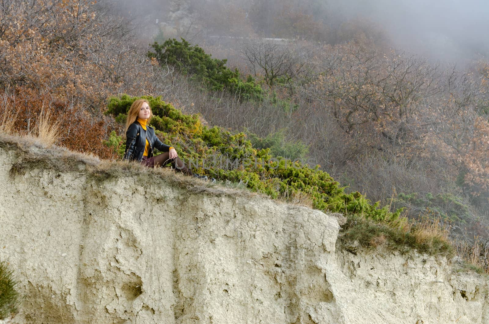 A girl sits on a hillock in the mountains and enjoys a wonderful view