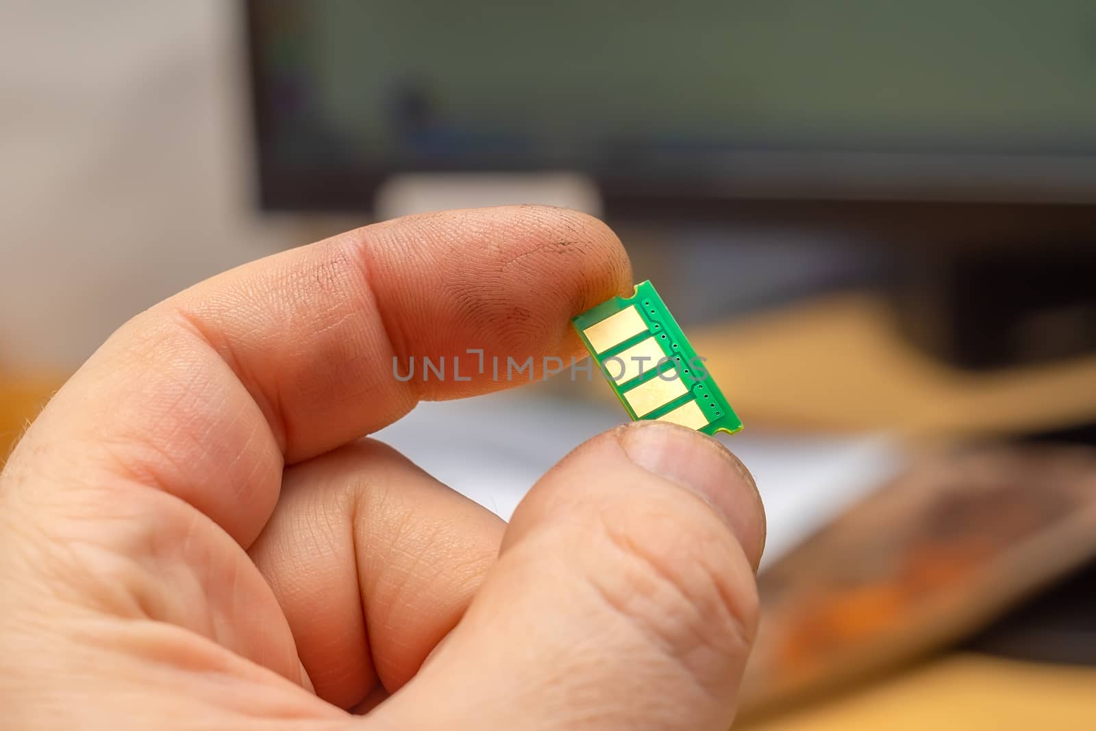 close up, microchip with copper contacts in the hand of a person on the background of a monitor, computer
