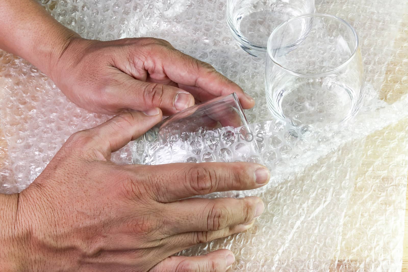hand of man hold bubble wrap cover glass for protection product  by piyaphun
