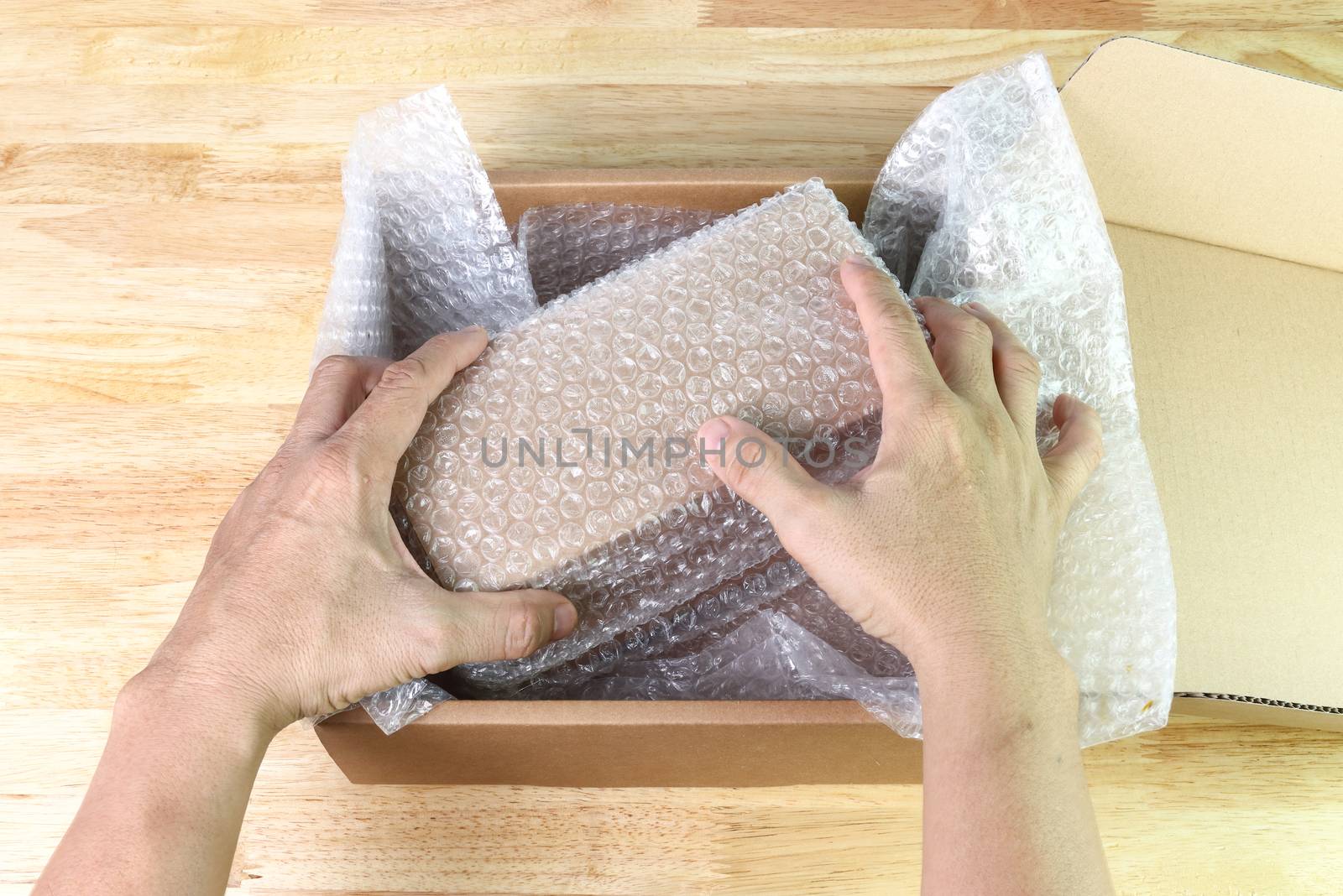 hand of man hold Bubbles covering the box by bubble wrap for protection product cracked  or insurance During transit  
