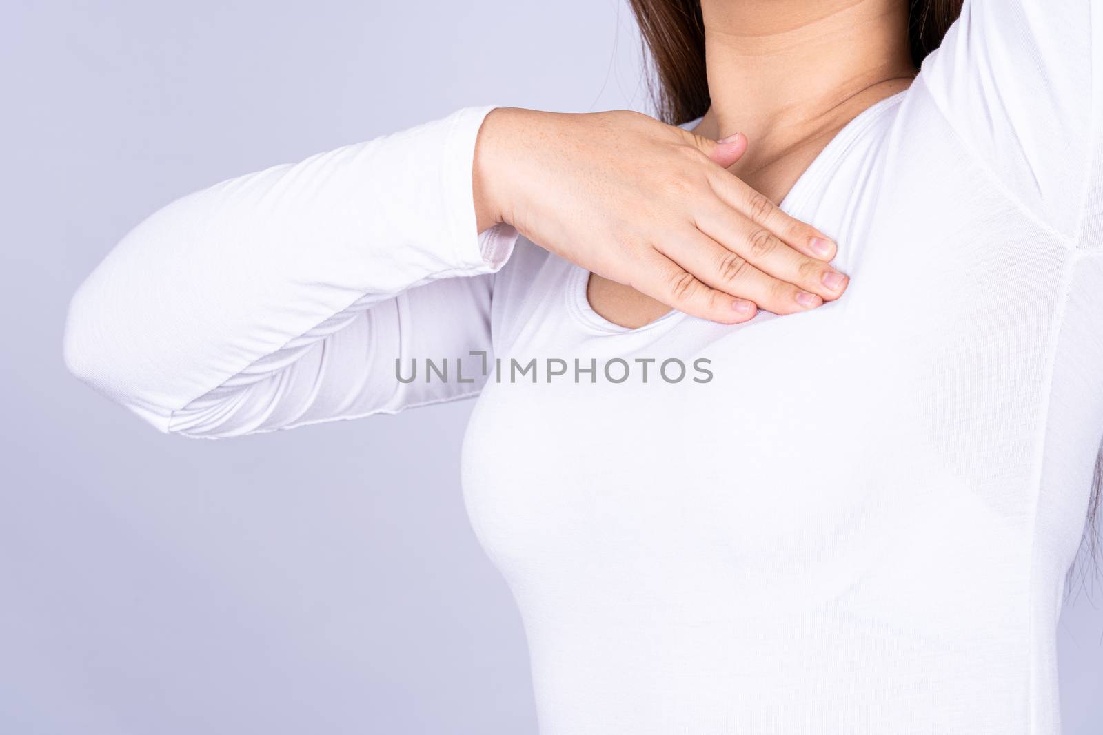 Woman hands doing breast self exam for checking lumps and signs of breast cancer on grey background. Medical, healthcare for advertising concept.