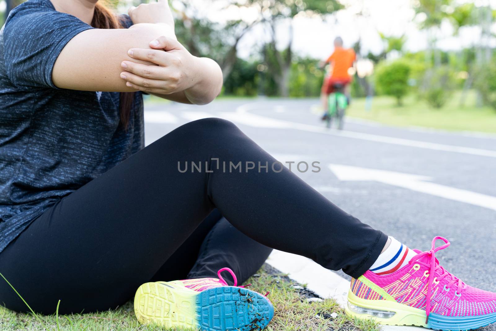 Asian woman suffering from arm and elbow pain from jogging and running outside at the park. Accident from sport and exercise concept.